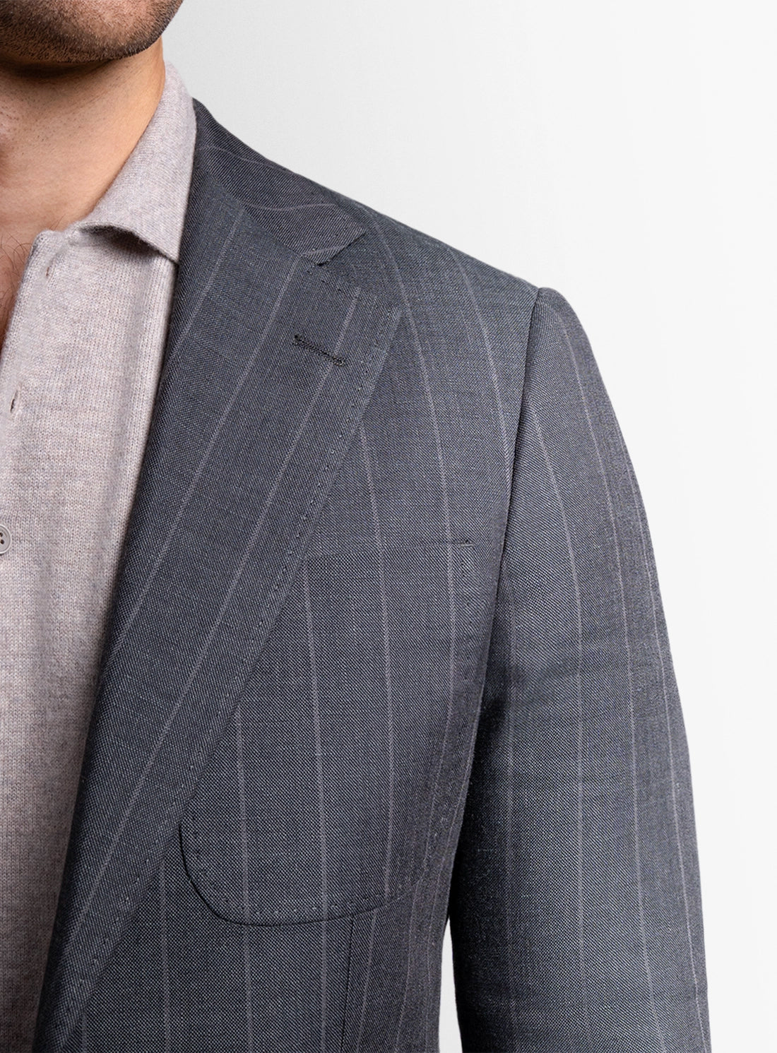 Gray pinstripe suit jacket worn by a person on a white background