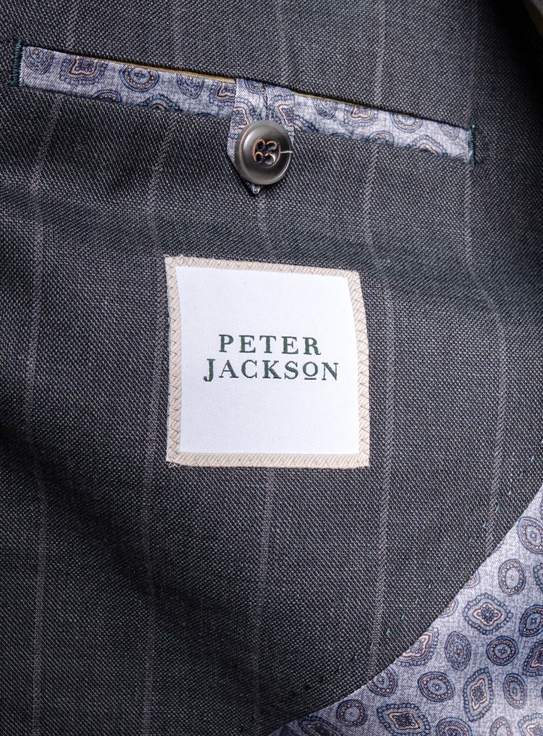 Close-up of a gray suit pocket with 'Peter Jackson' label