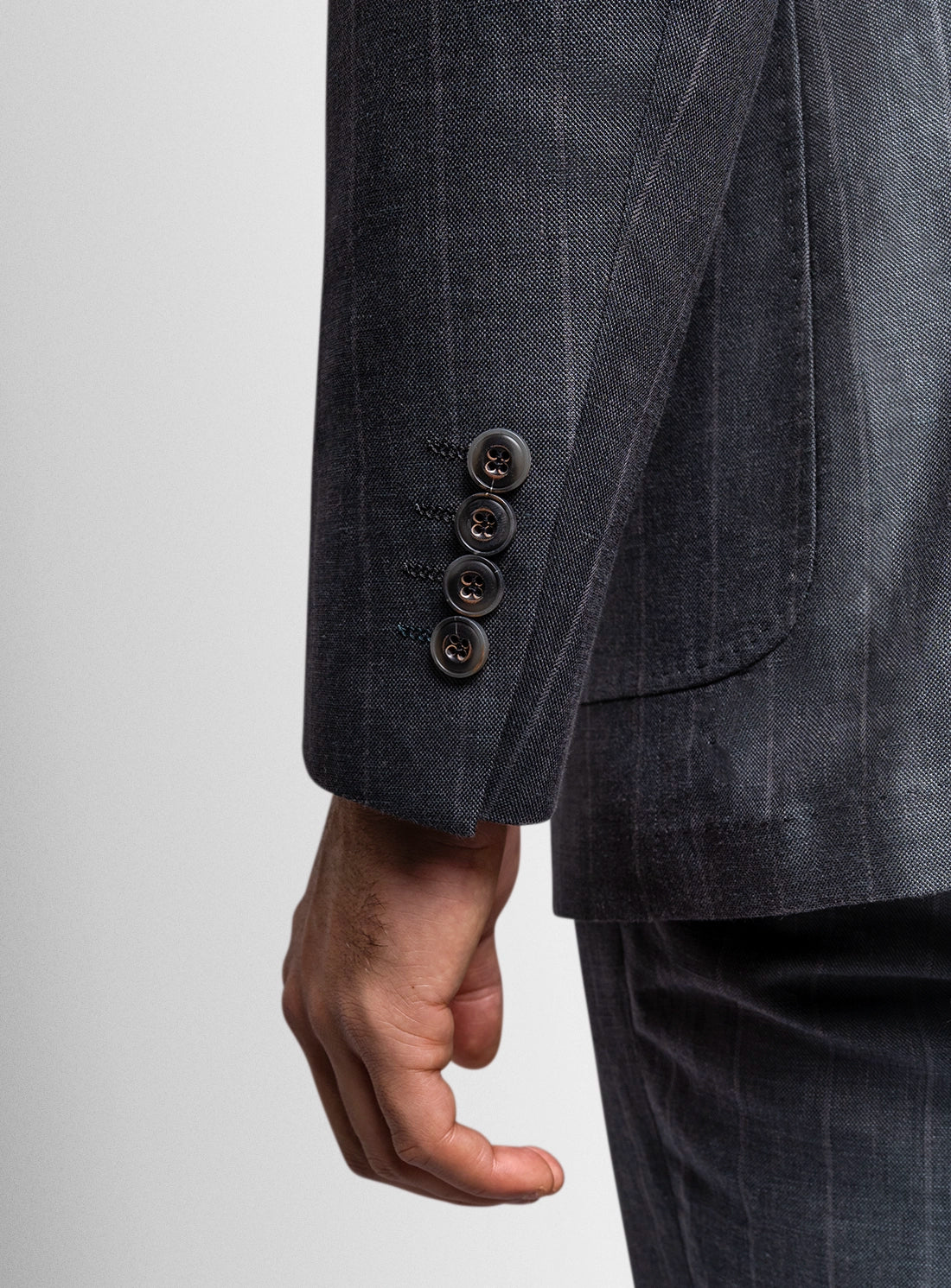 Dark gray suit jacket with three buttons on a light gray background