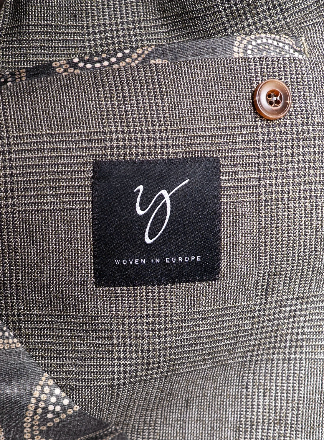 Close-up of a gray textured fabric with a brand label and button.