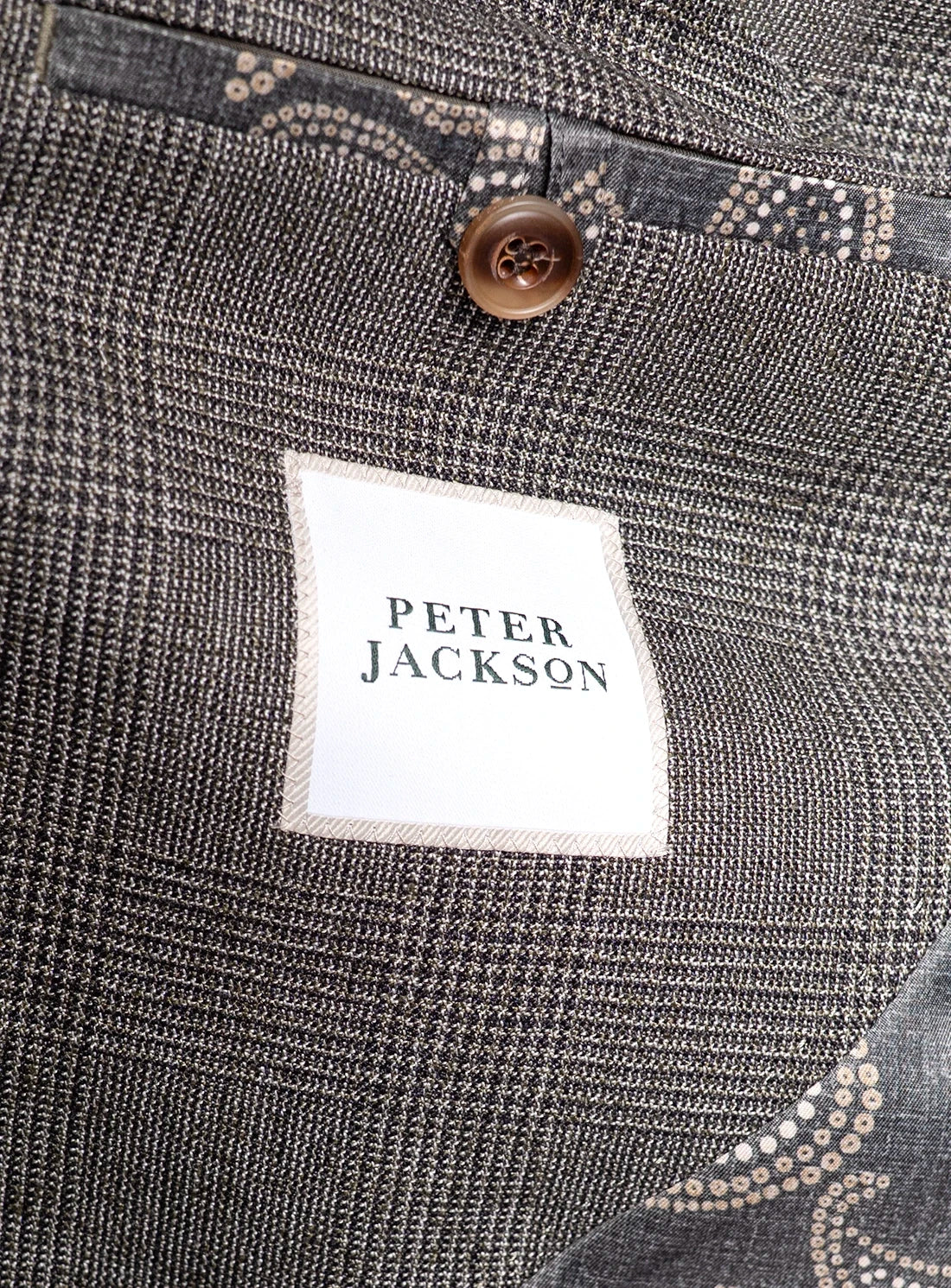 Close-up of a gray textured fabric with a brand label and button.