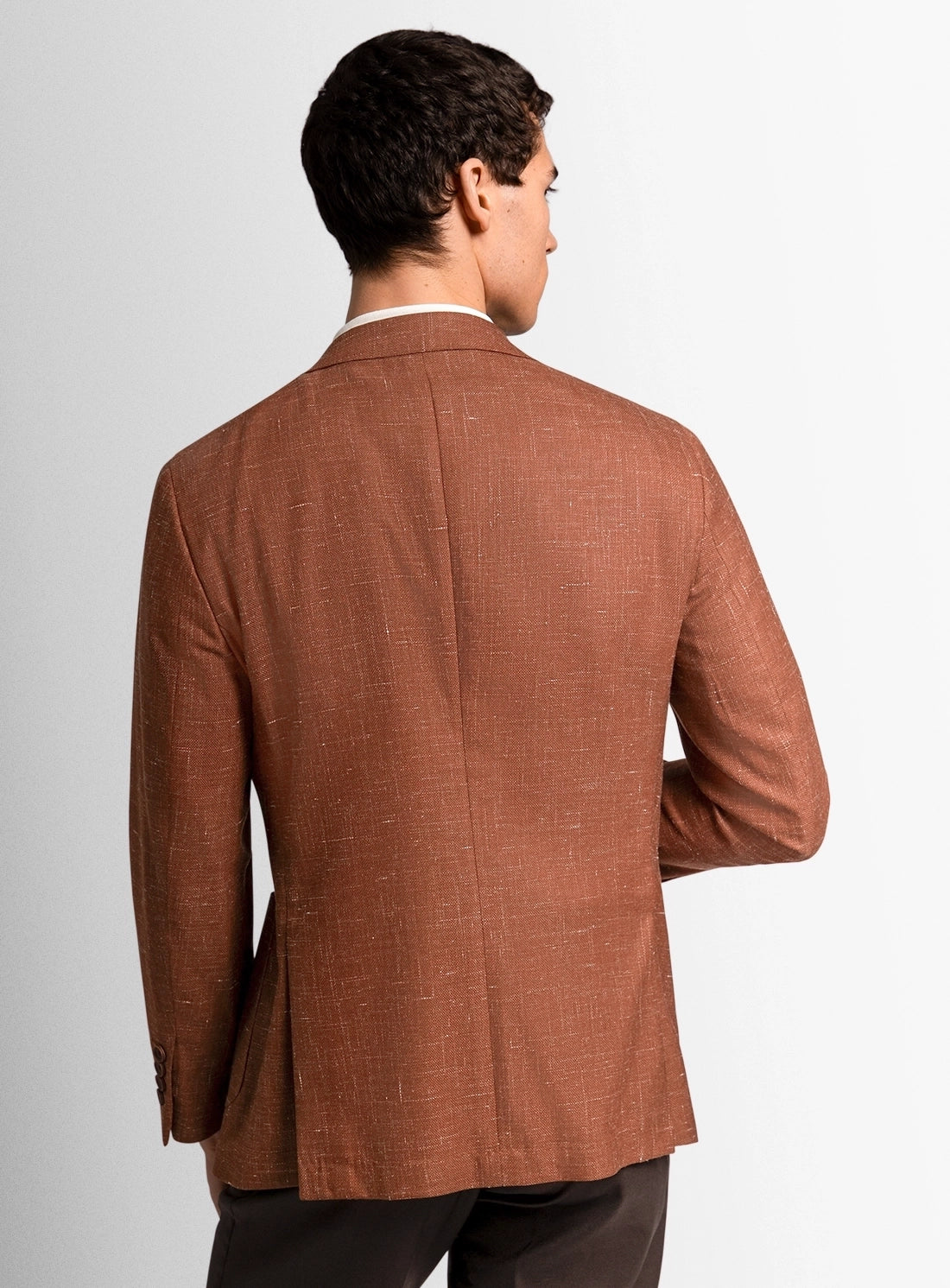 Man wearing a brown suit jacket on a plain background