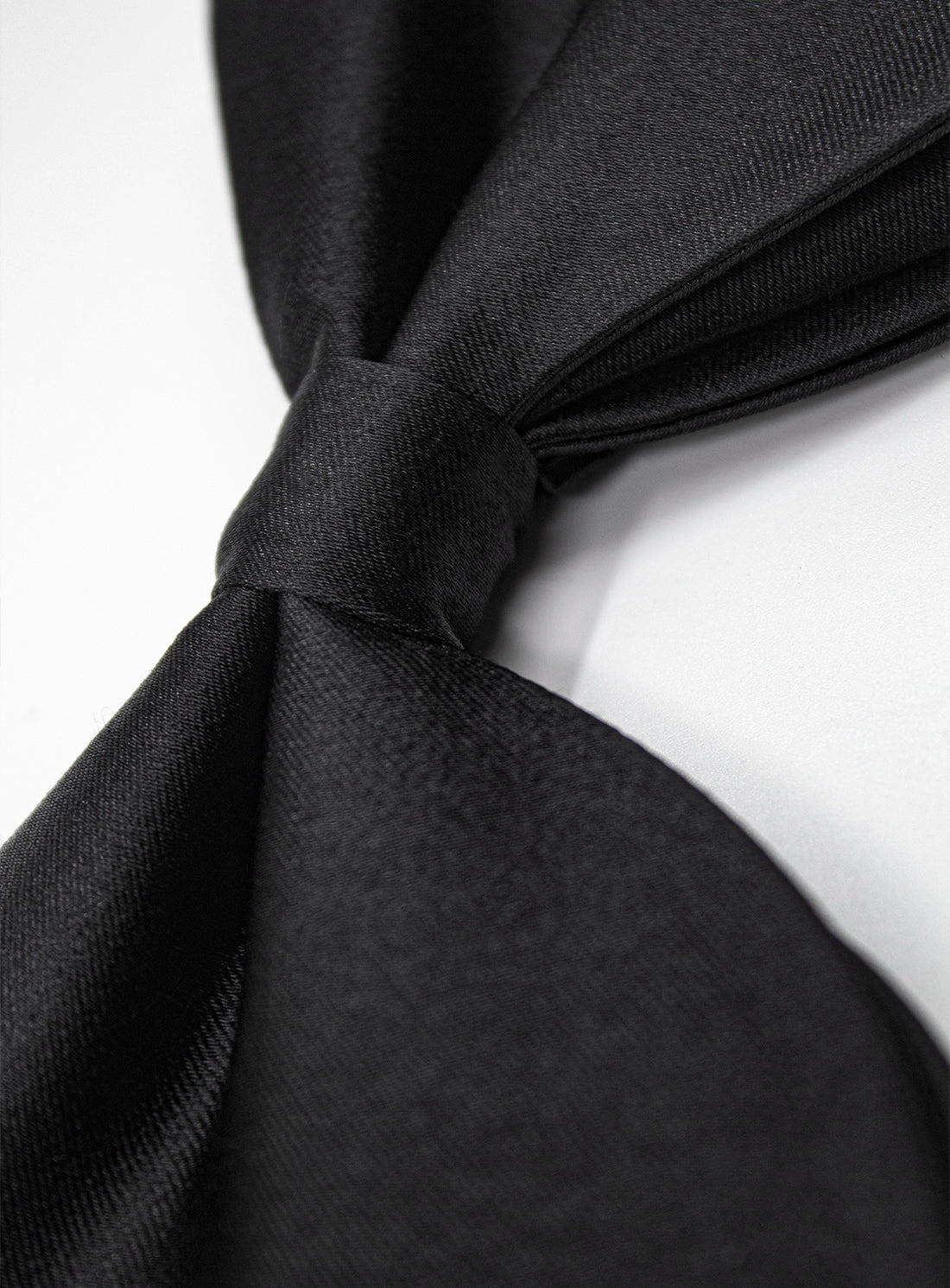 Close-up of a black tie knot on a white background