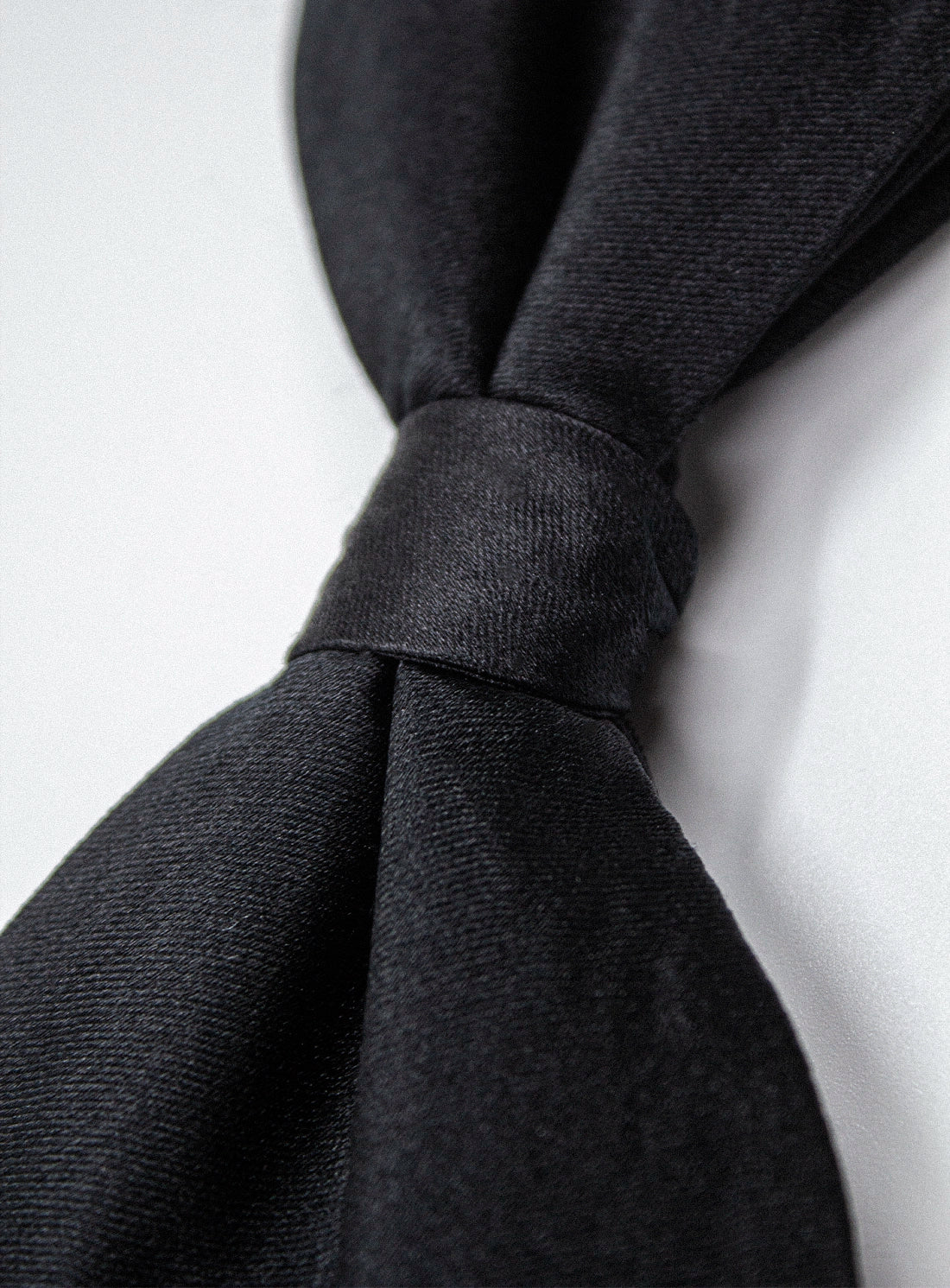 Close-up of a black tie knot on a white background