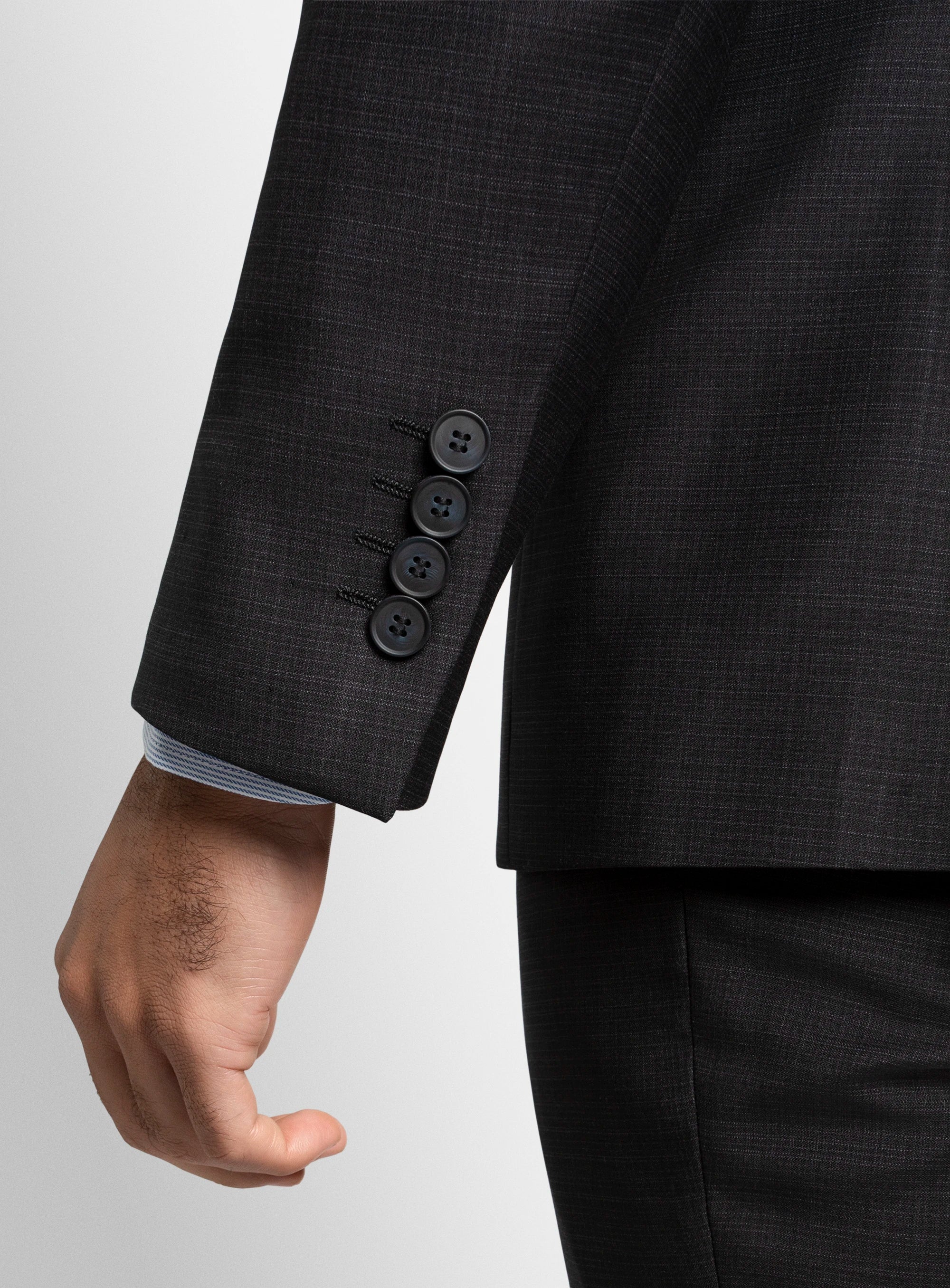 Close-up of a dark gray suit jacket with three buttons on a light gray background