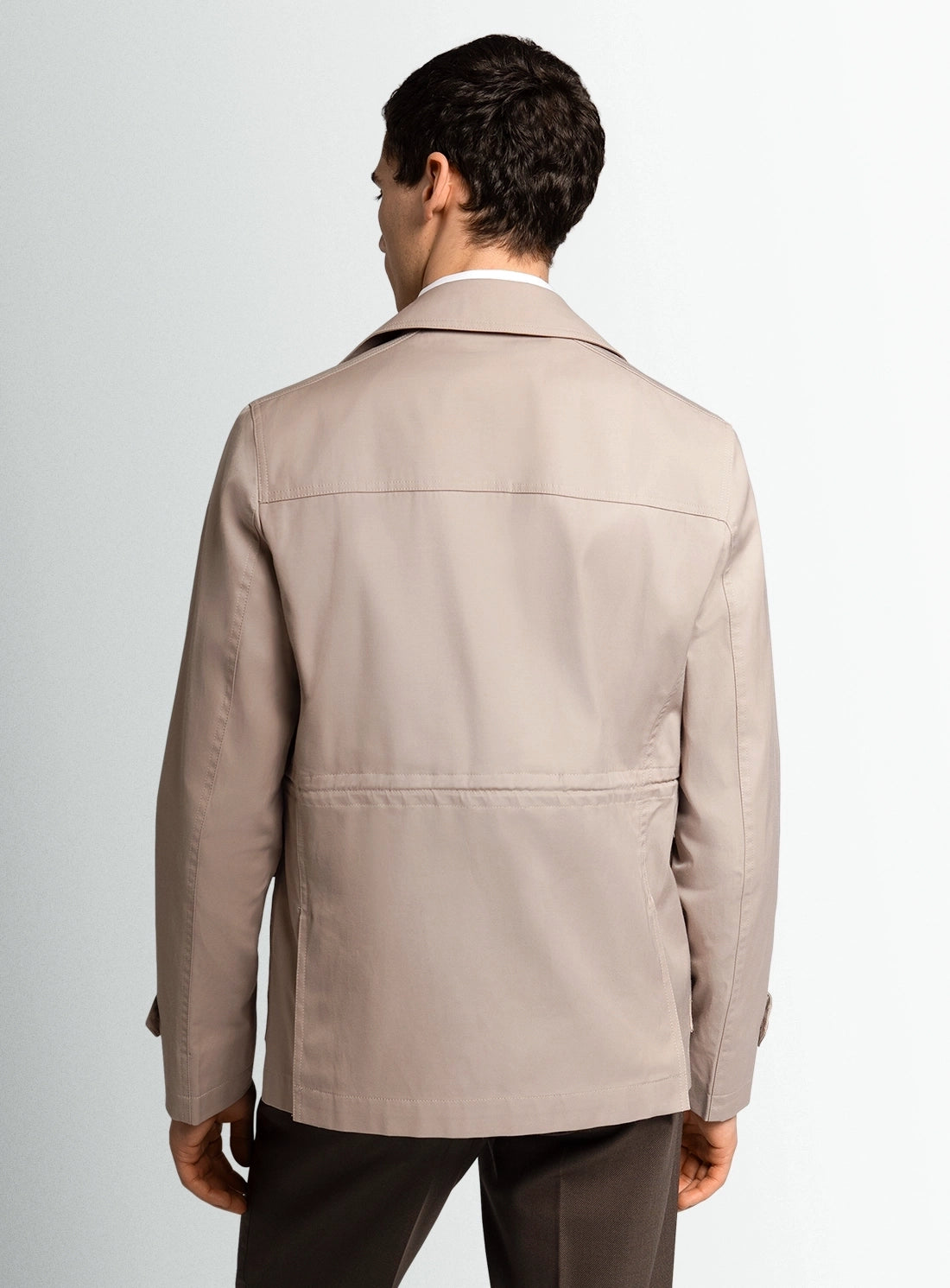 Man wearing a beige jacket on a plain background