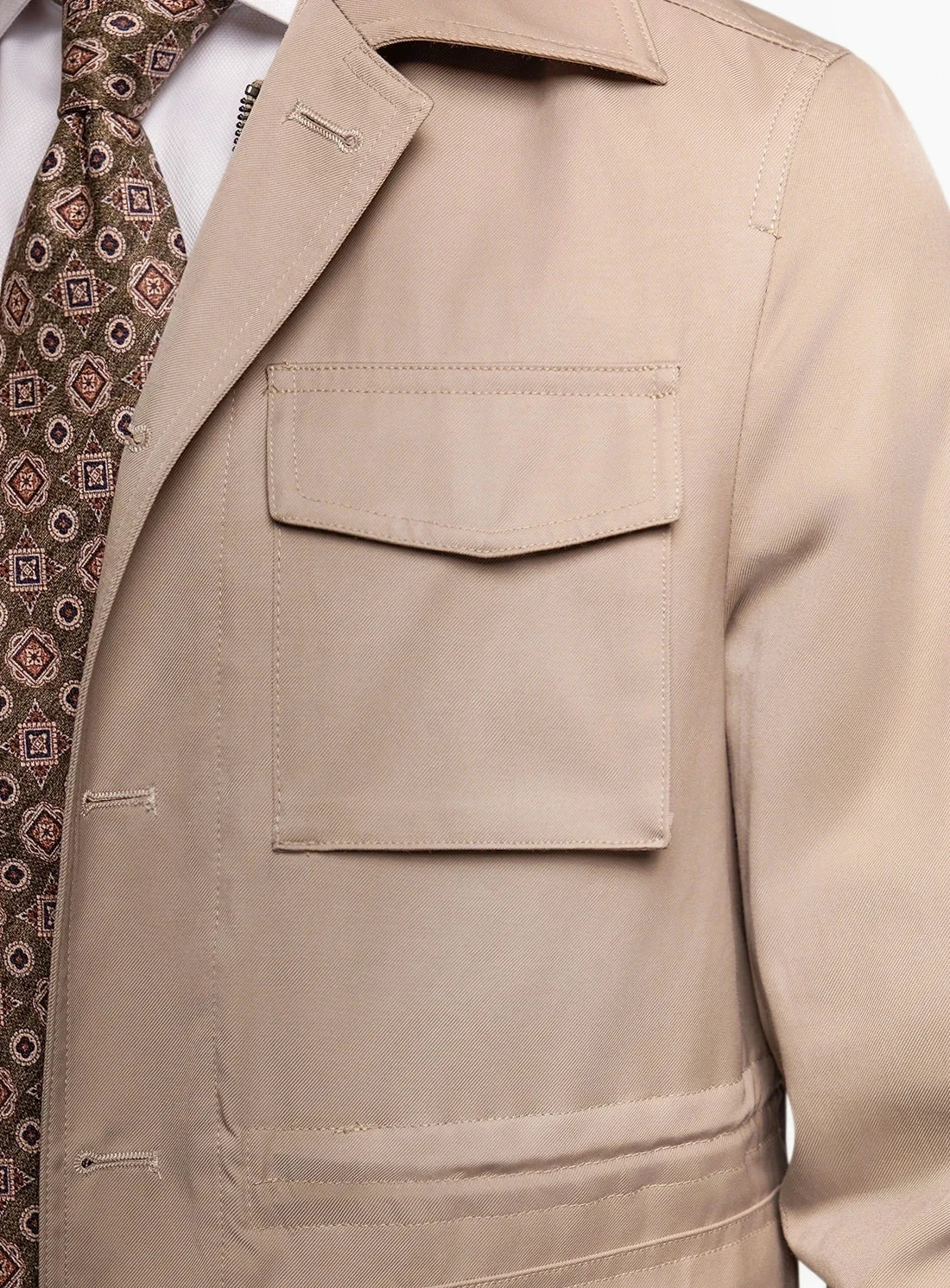 Close-up of a beige trench coat with a patterned tie.