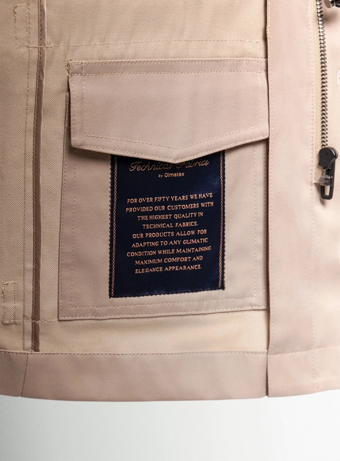 Close-up of a beige jacket with a brand label on a light gray background