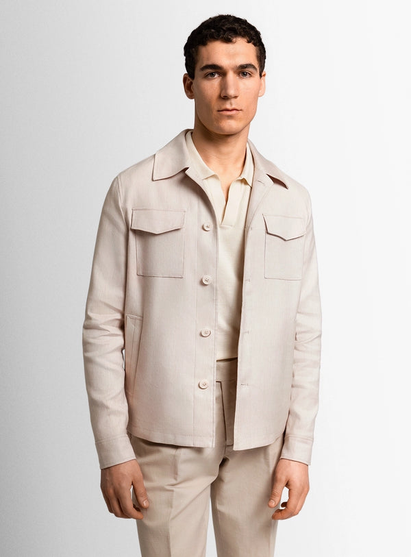 Man wearing a beige jacket and pants against a light gray background