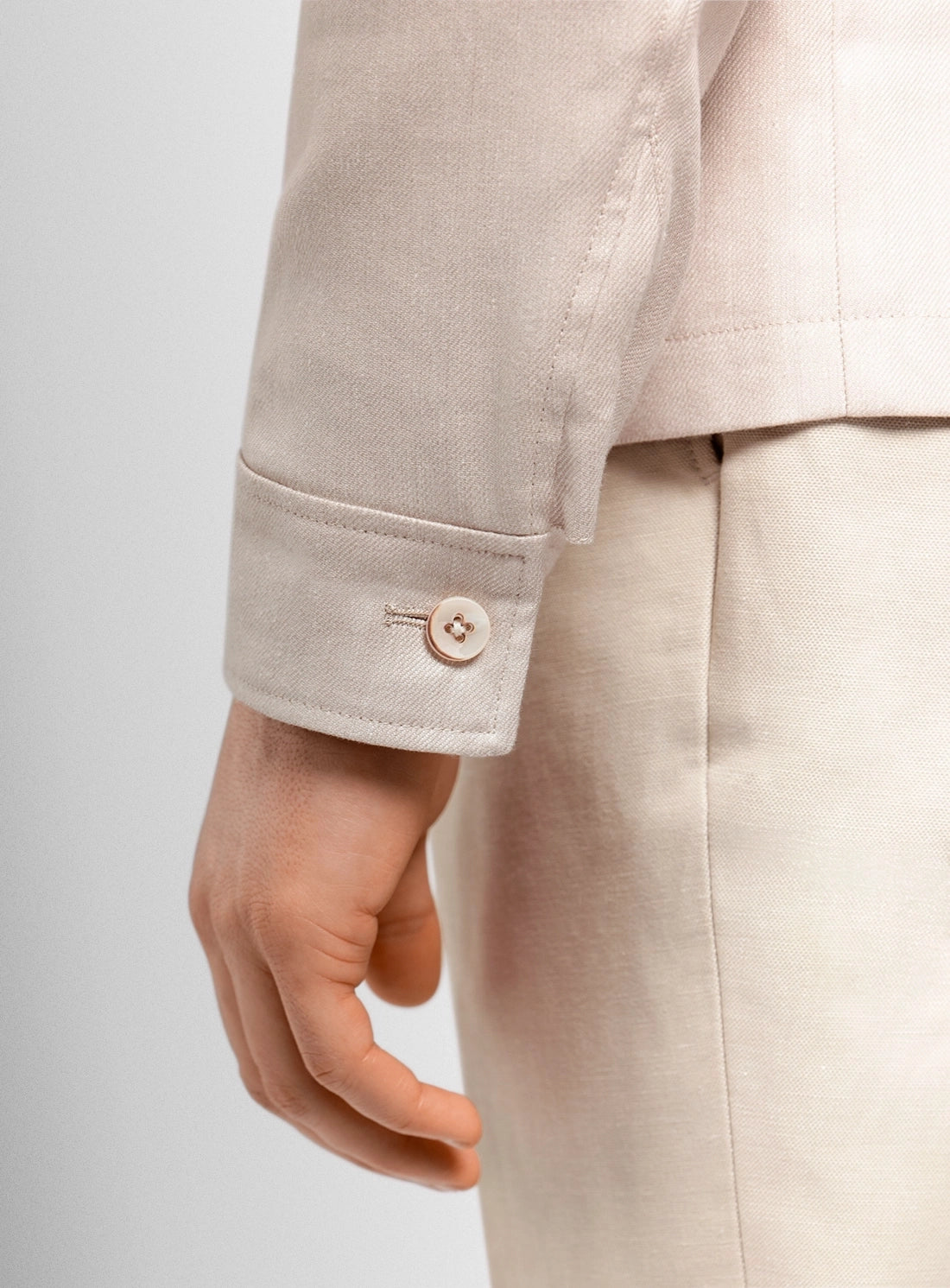 Close-up of a beige suit with a button on a light gray background
