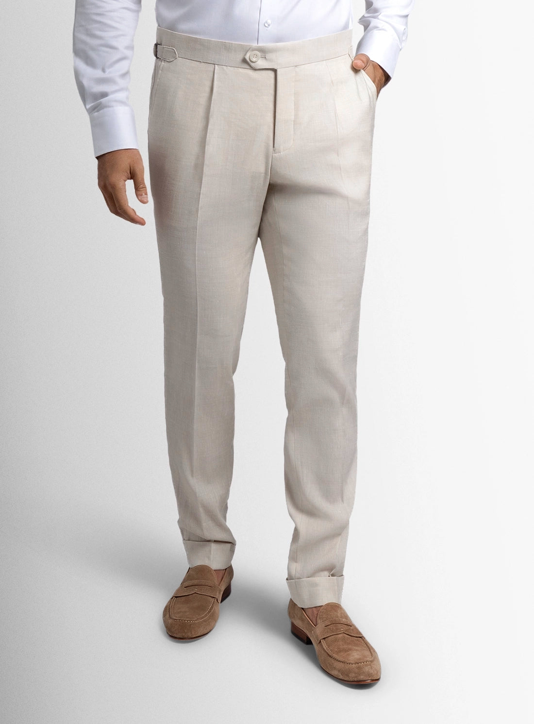 Beige dress pants worn with a white shirt and brown shoes on a light gray background