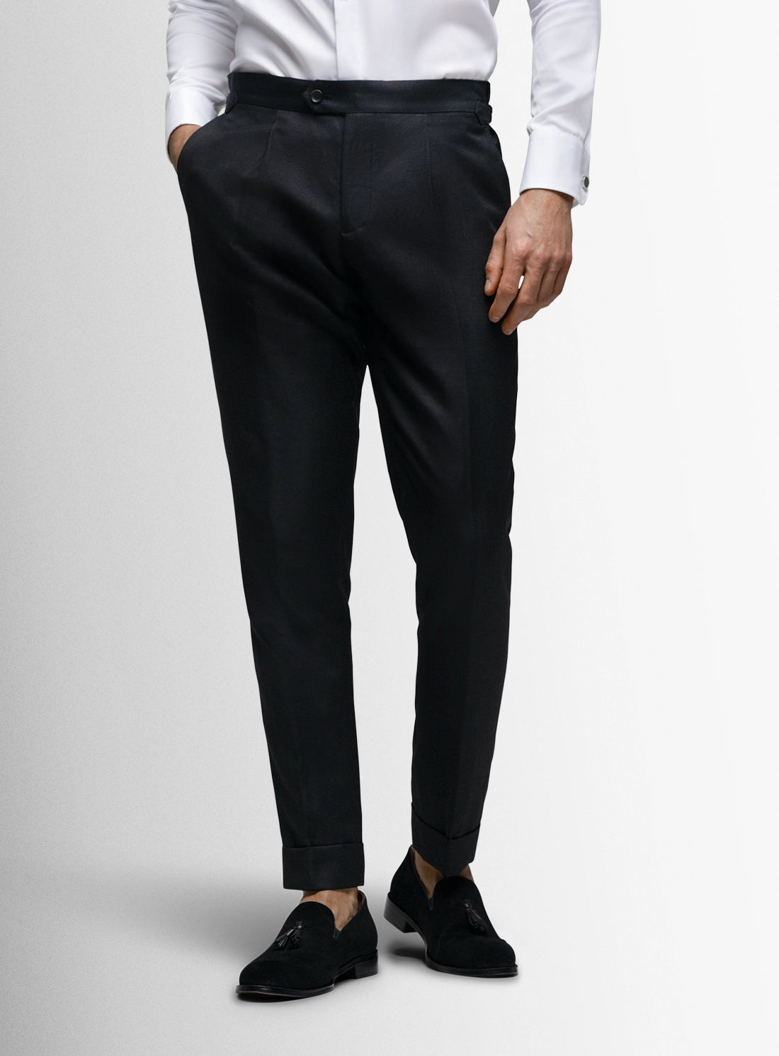 Person wearing black dress pants with a white shirt on a light gray background