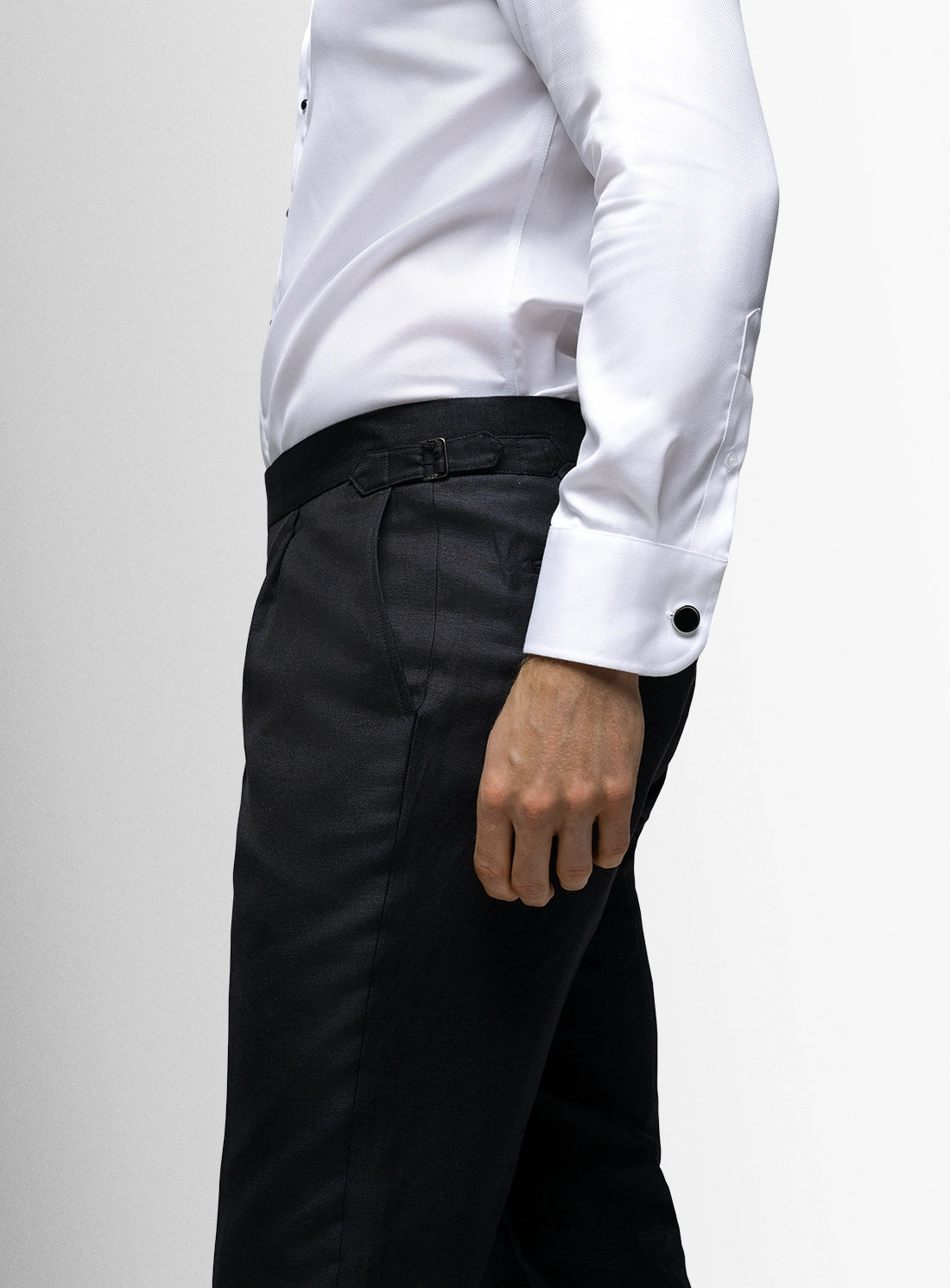 Person wearing a white shirt and black pants on a light gray background