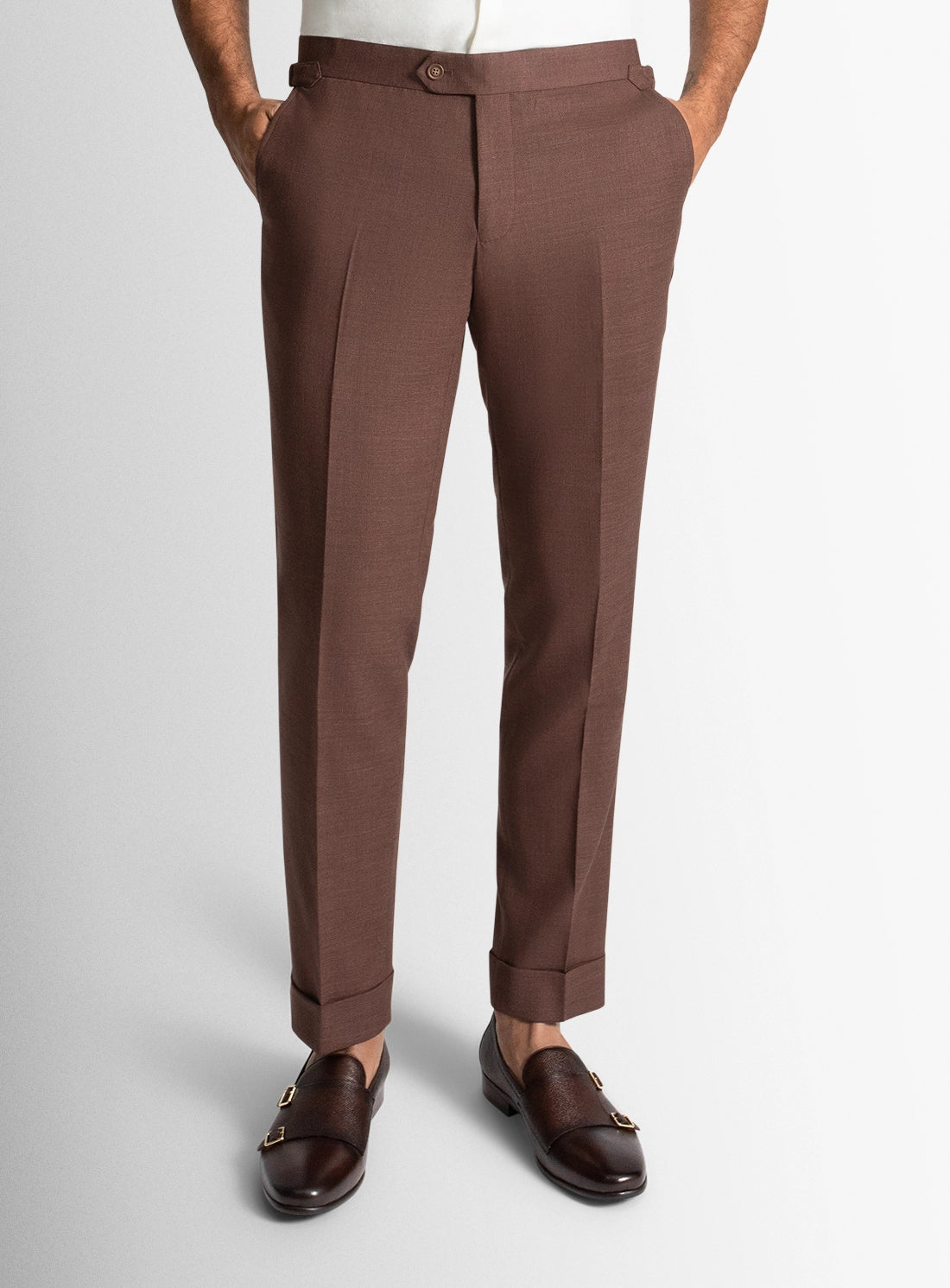 Brown dress pants worn by a person on a light gray background