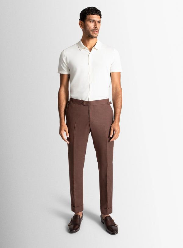 Man wearing a white shirt and brown pants on a light gray background