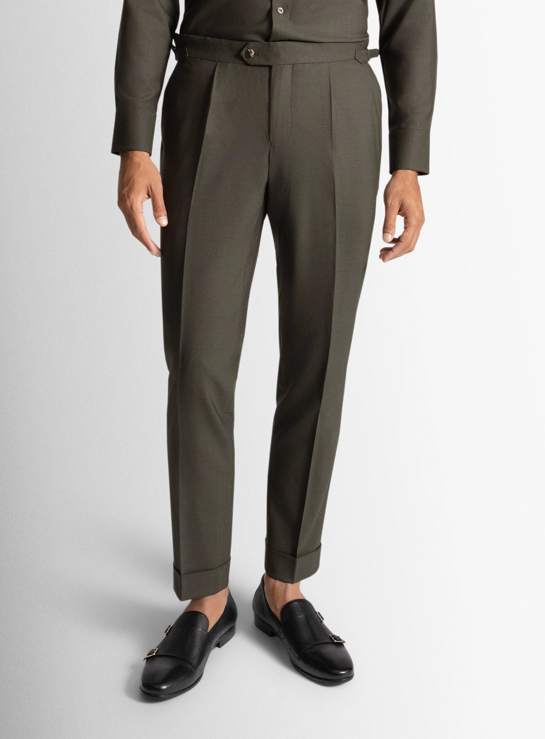 Person wearing a green suit with a belt on a gray background