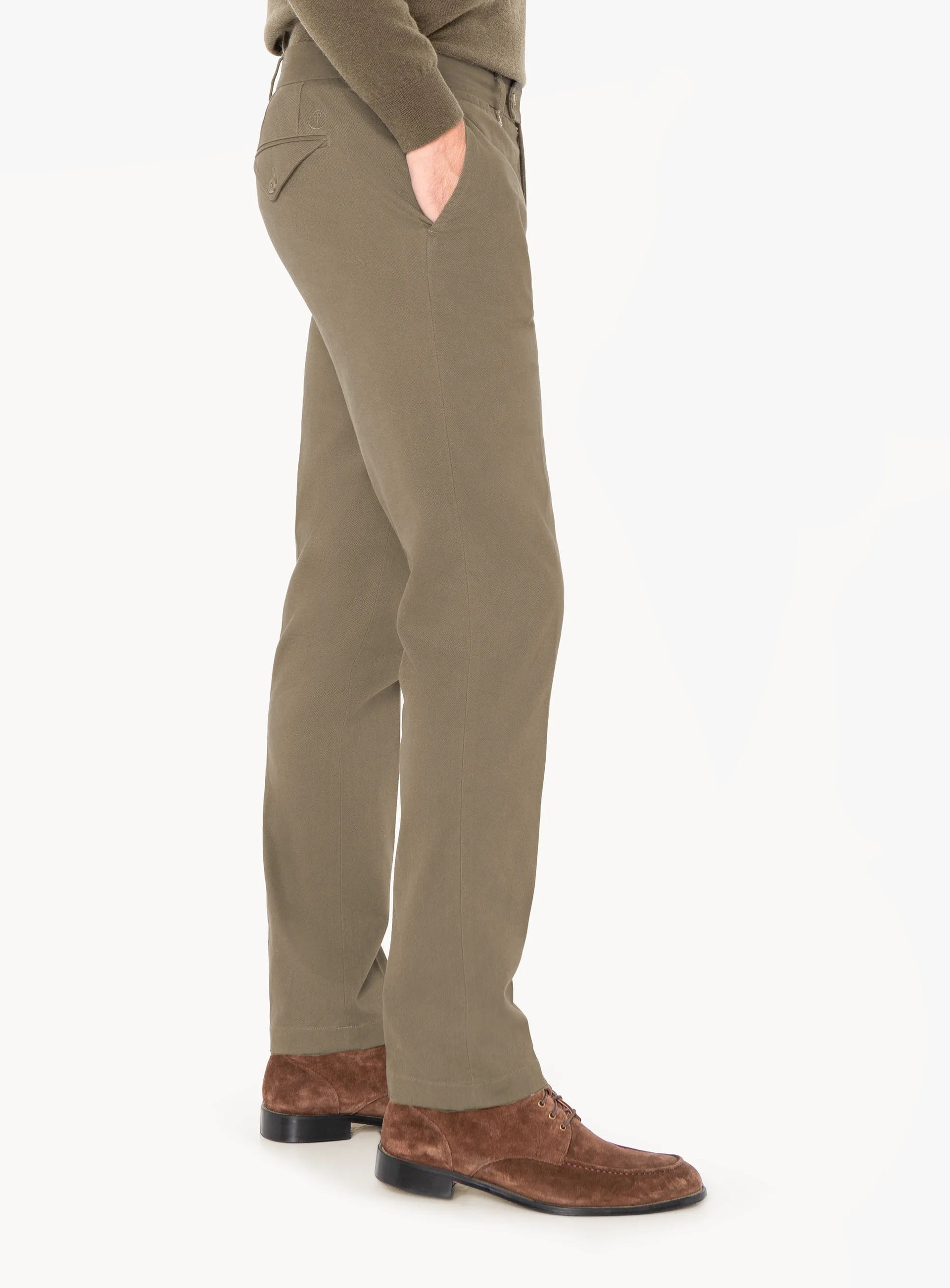 Person wearing olive green pants and brown shoes on a white background