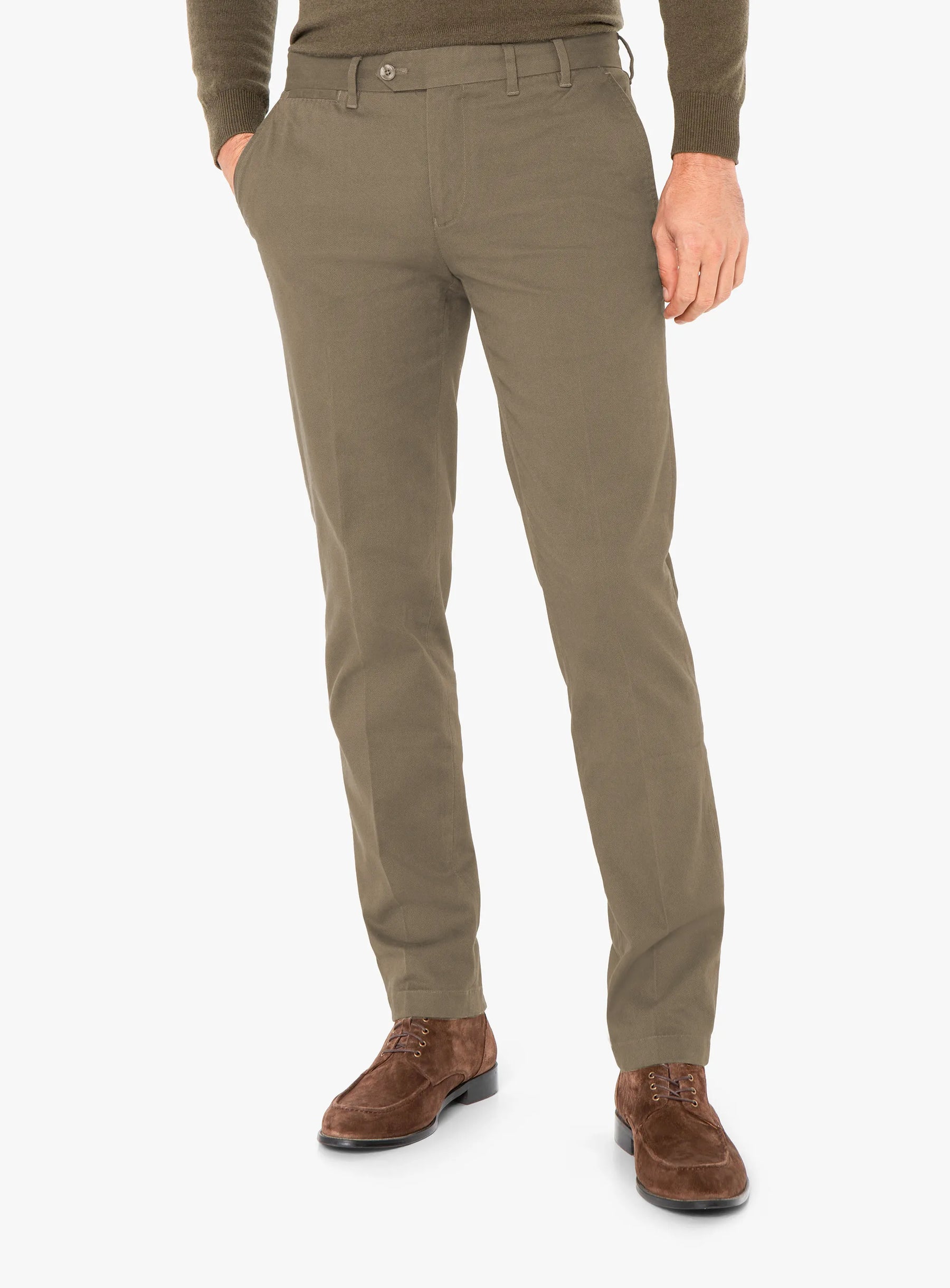 Person wearing olive green pants and brown shoes on a white background