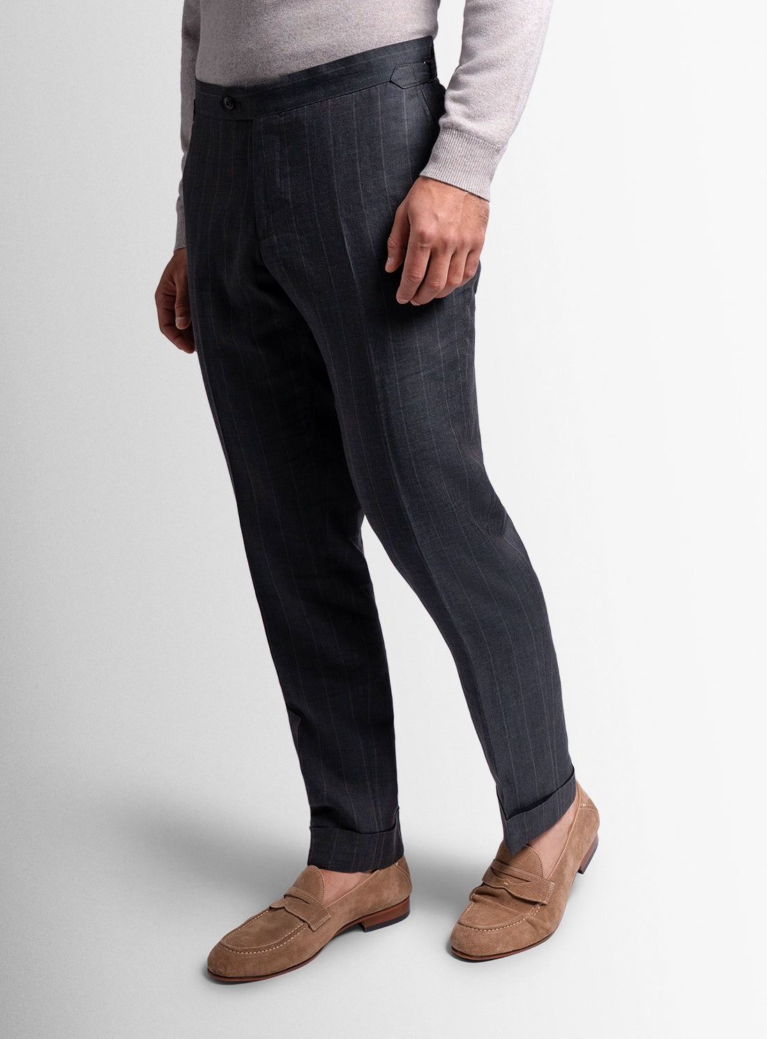 Person wearing dark pinstripe pants with a light gray sweater and brown shoes on a white background
