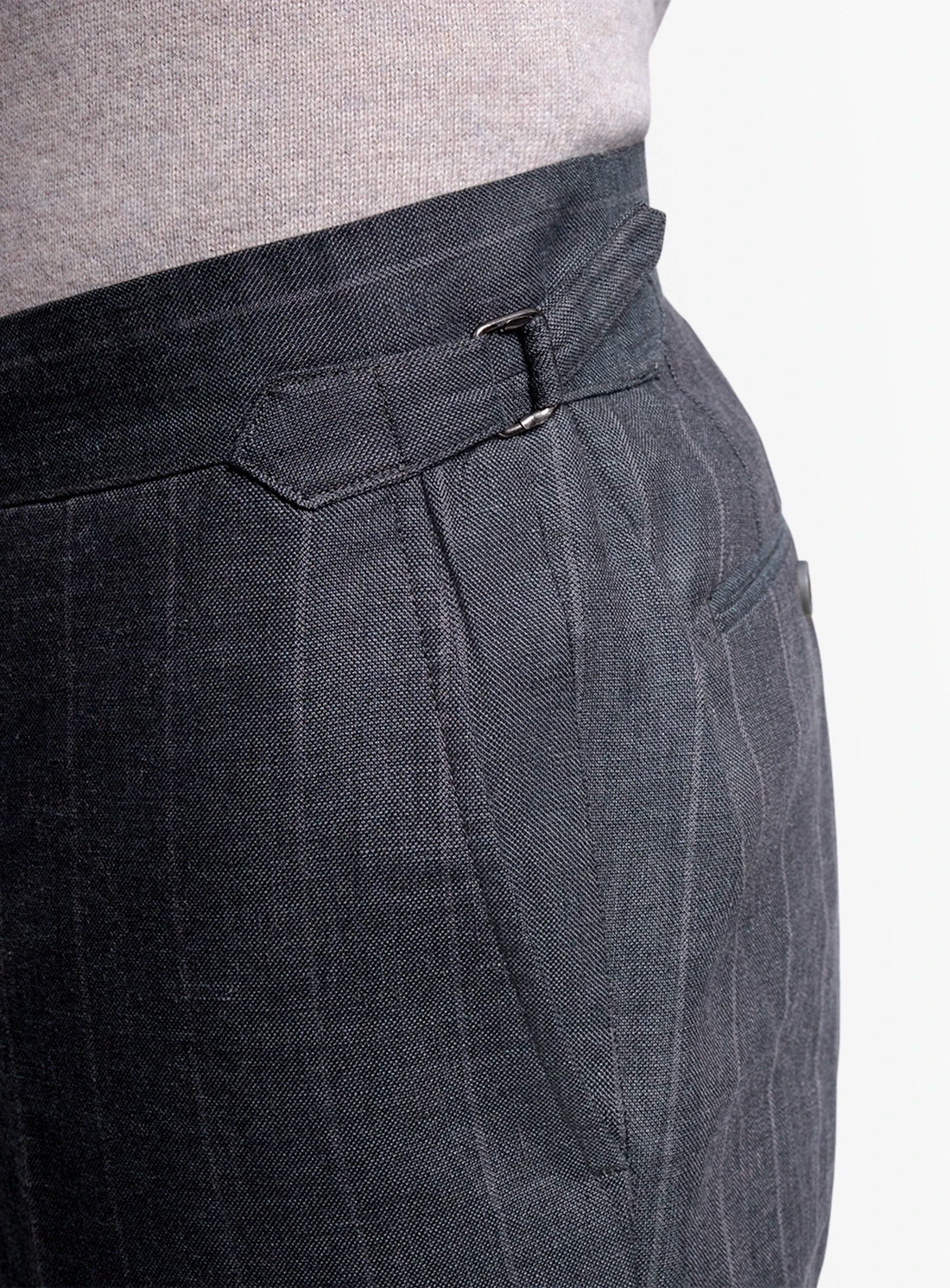 Close-up of dark gray checkered pants with a belt on a light gray background