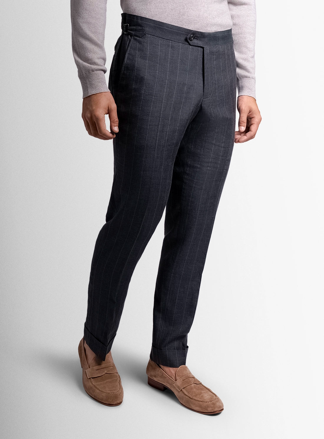 Dark gray suit pants worn by a person on a light gray background