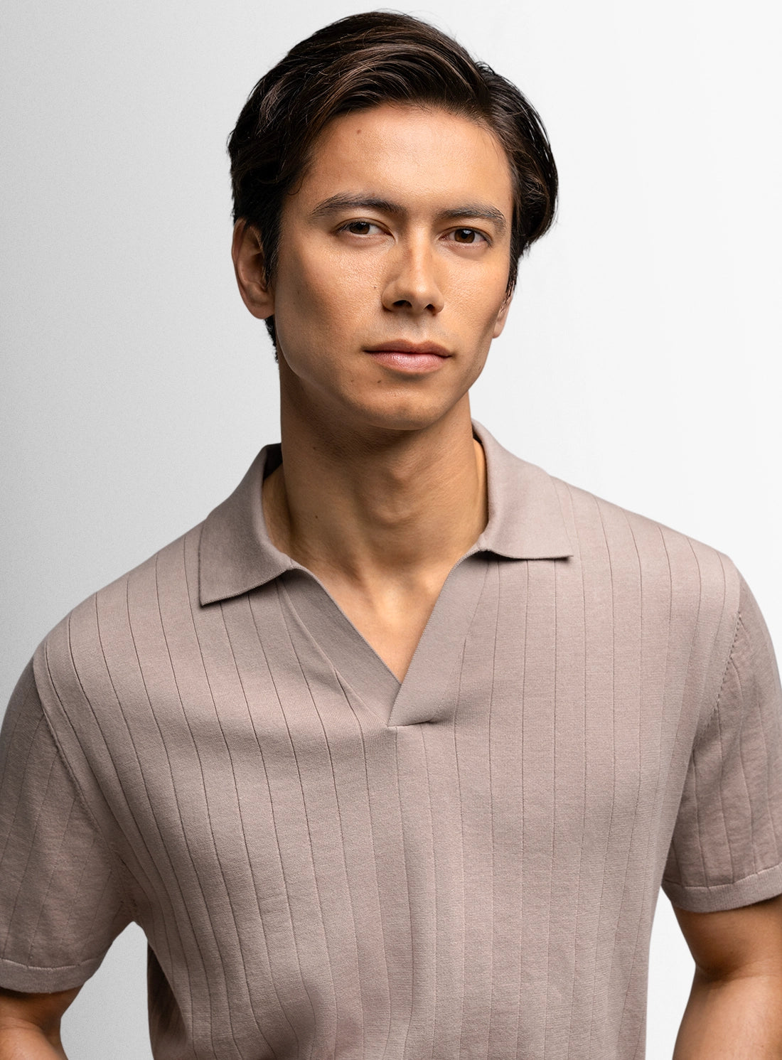 Man wearing a beige polo shirt against a gray background