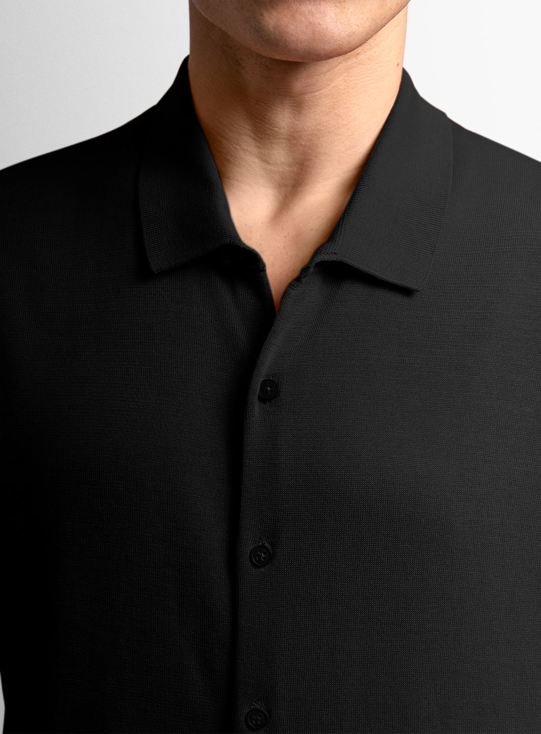 Close-up of a person wearing a black shirt with a plain background