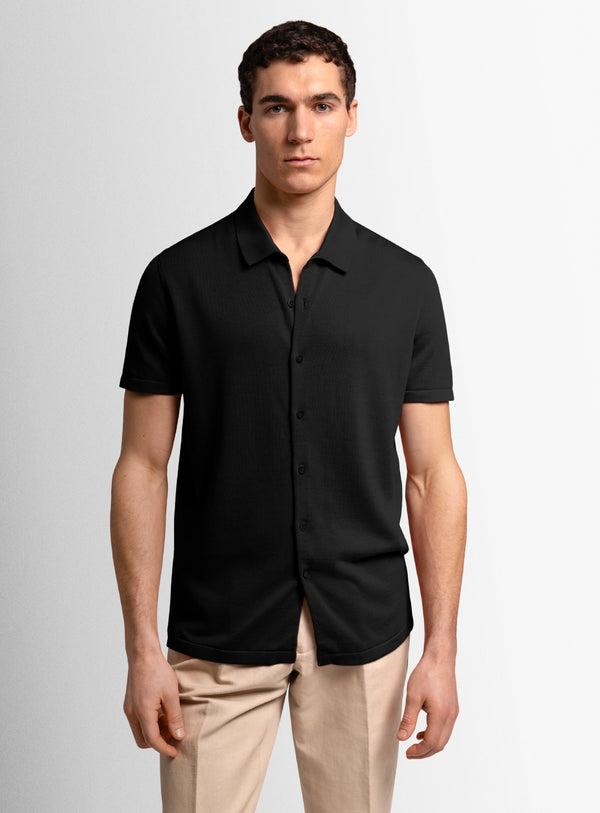 Man wearing a black short-sleeve shirt against a plain background