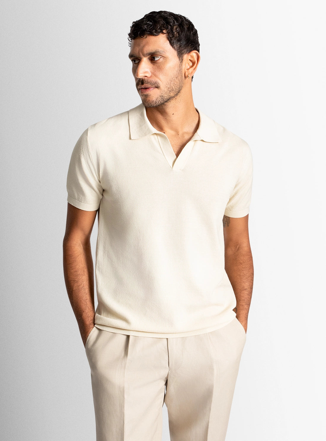 Man wearing a beige polo shirt and pants against a light gray background