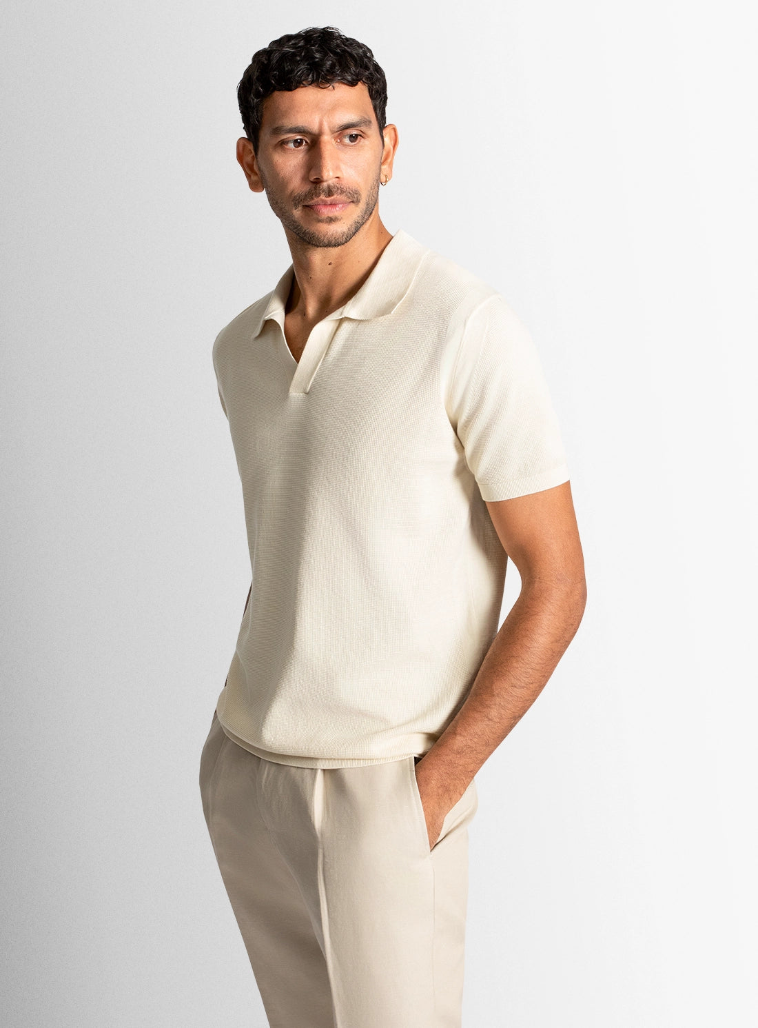 Man wearing a beige polo shirt and pants against a white background