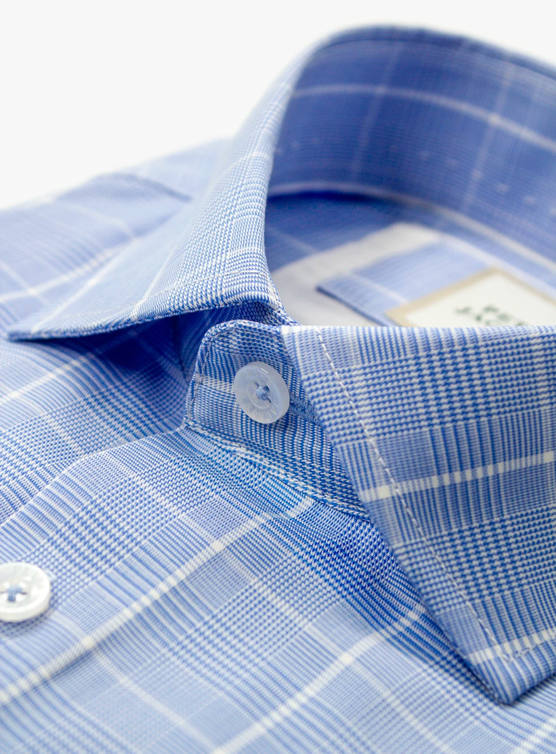 Close-up of a blue checkered shirt with a button and collar detail.