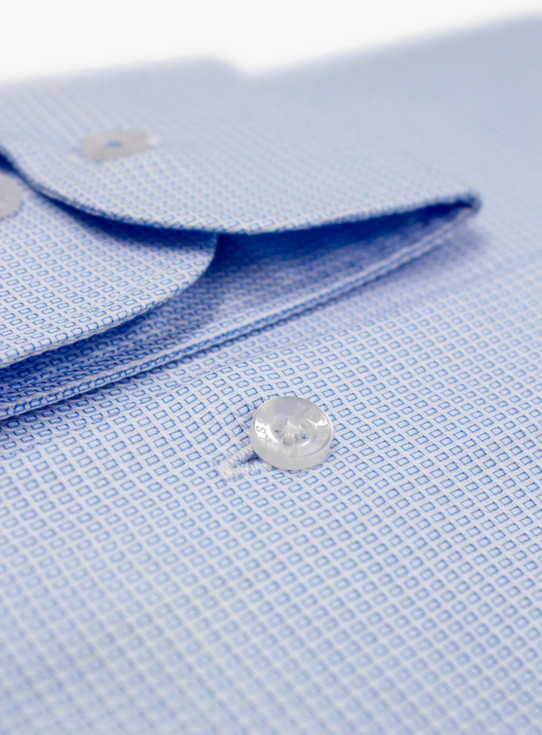 Close-up of a light blue textured shirt with a button on a white background