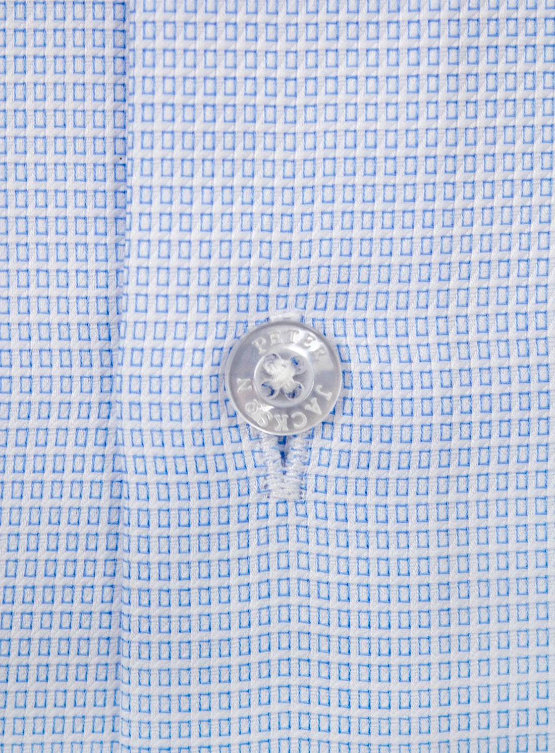 Close-up of a button on a light blue checkered shirt