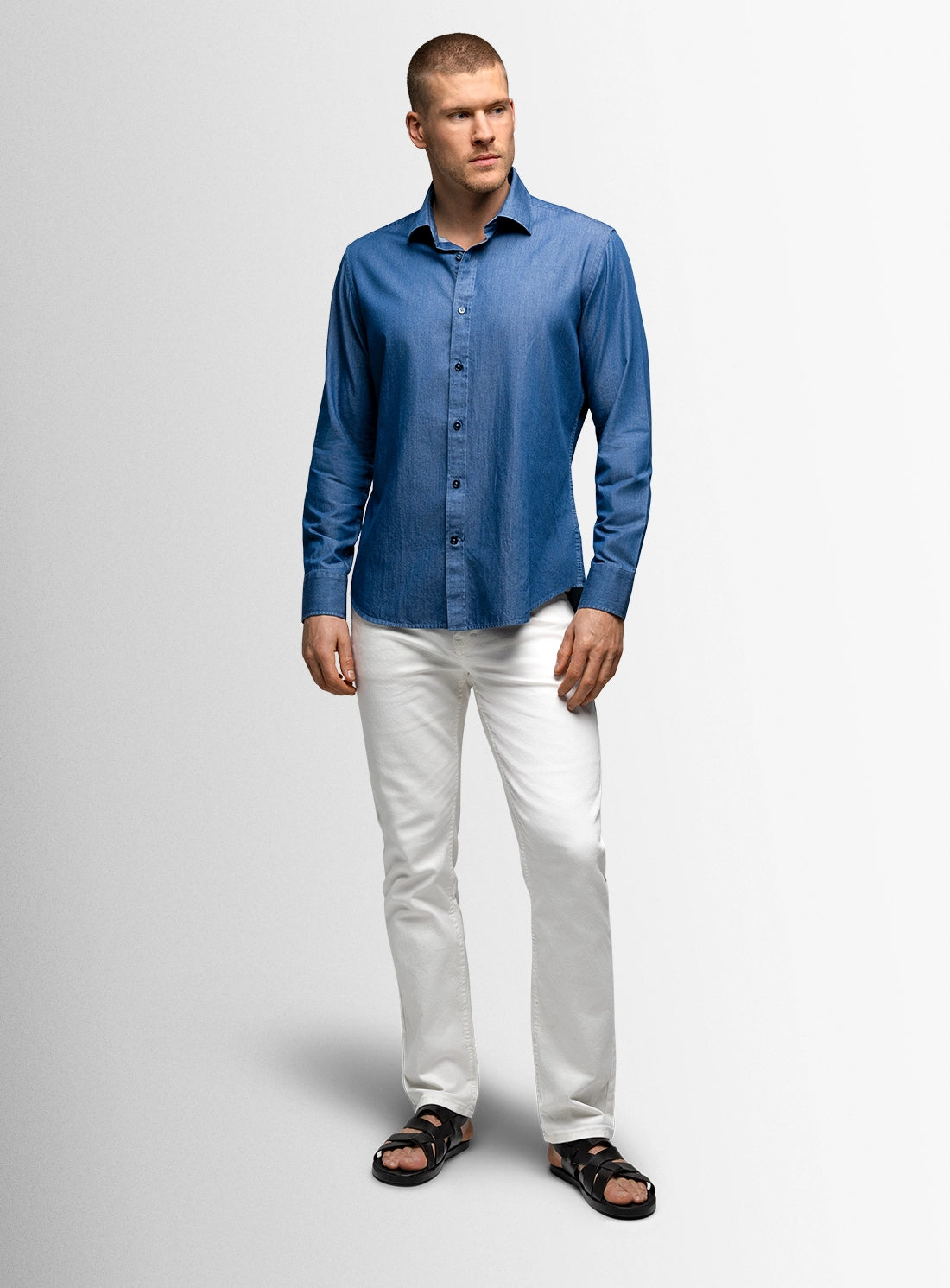 Man wearing a blue shirt and white pants on a gray background