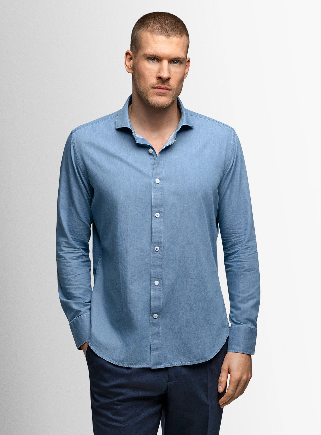 Man wearing a light blue shirt against a gray background