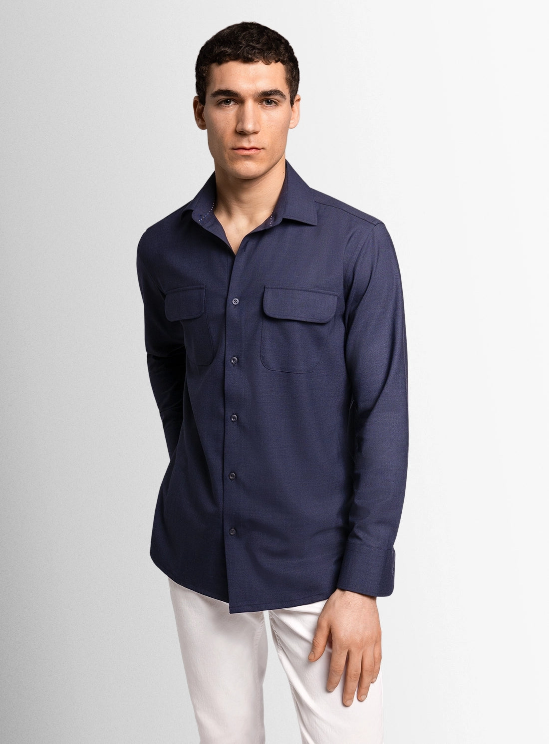 Man wearing a navy blue shirt with two chest pockets on a light gray background