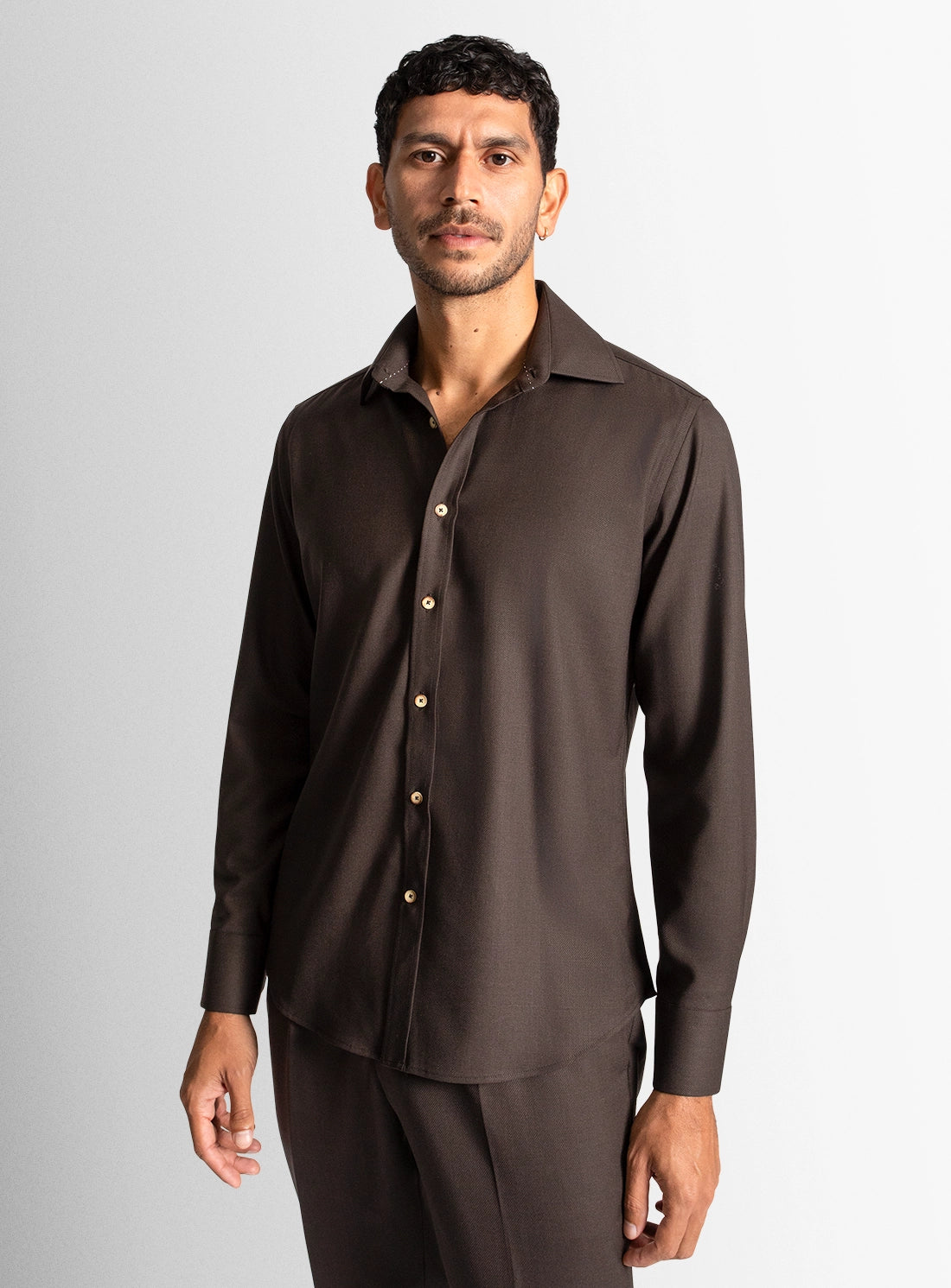 Man wearing a brown dress shirt and pants against a gray background
