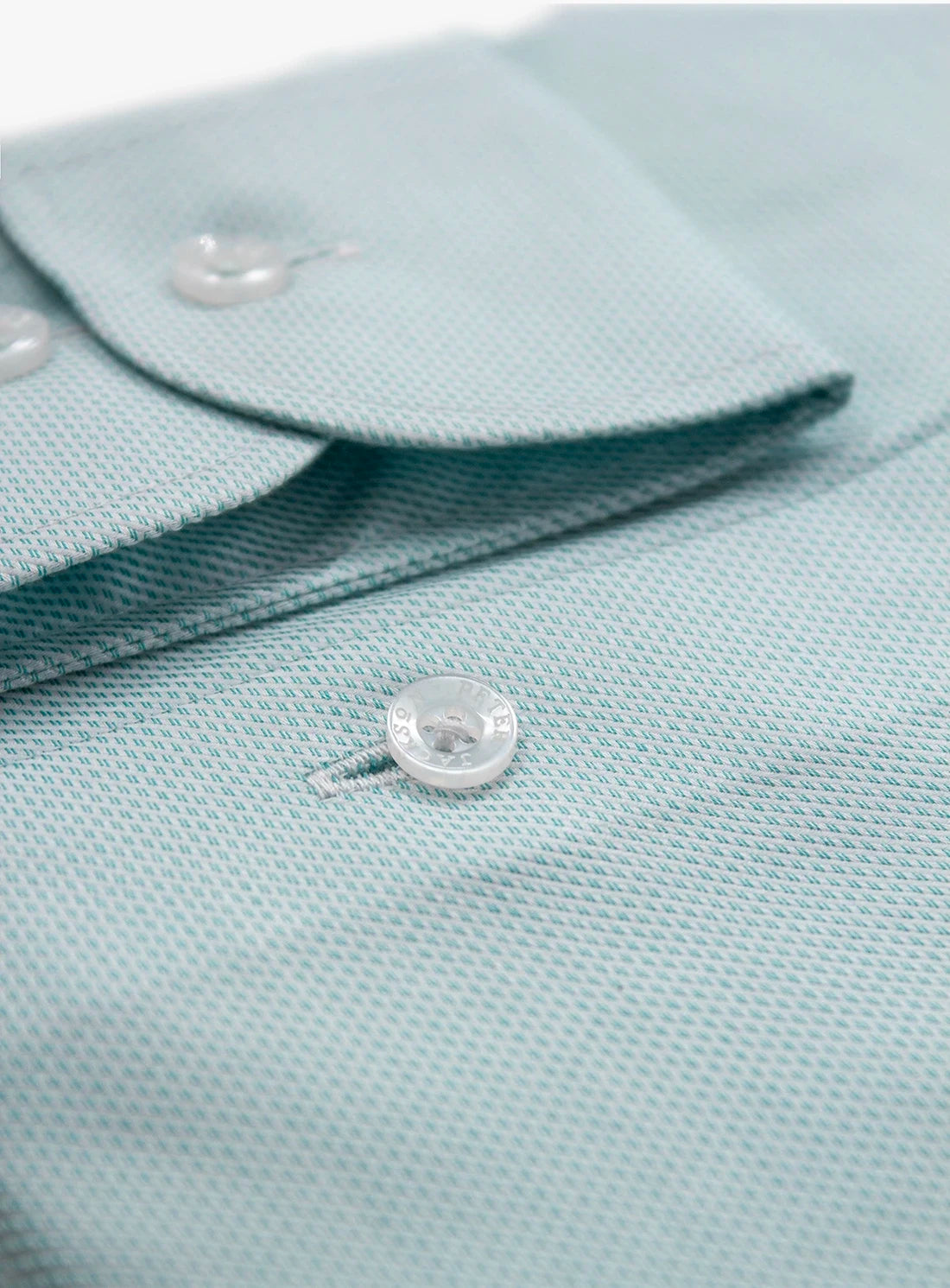 Close-up of a light blue polo shirt with buttons on a white background