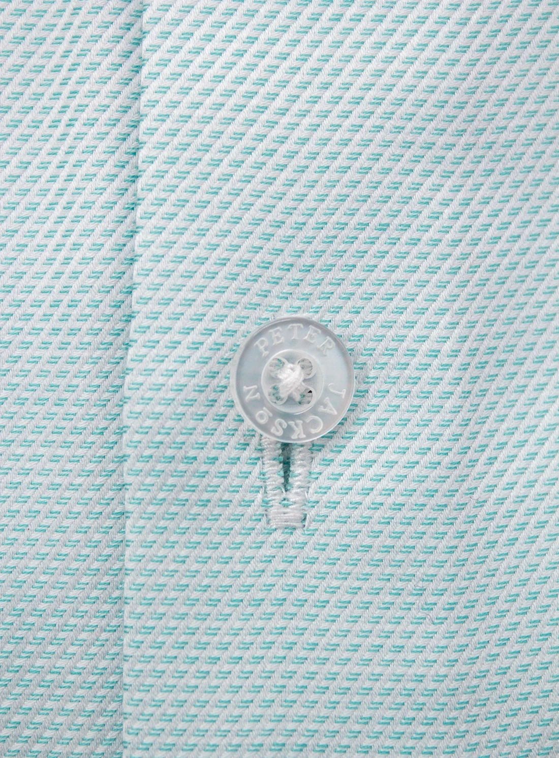 Close-up of a button on a light blue textured fabric