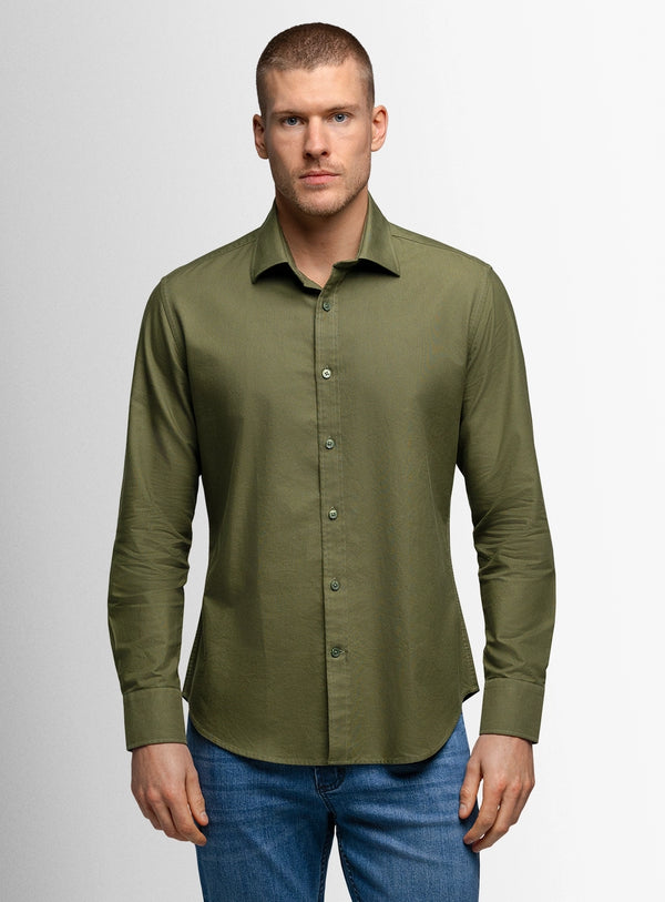 Man wearing a green button-up shirt and blue jeans on a gray background