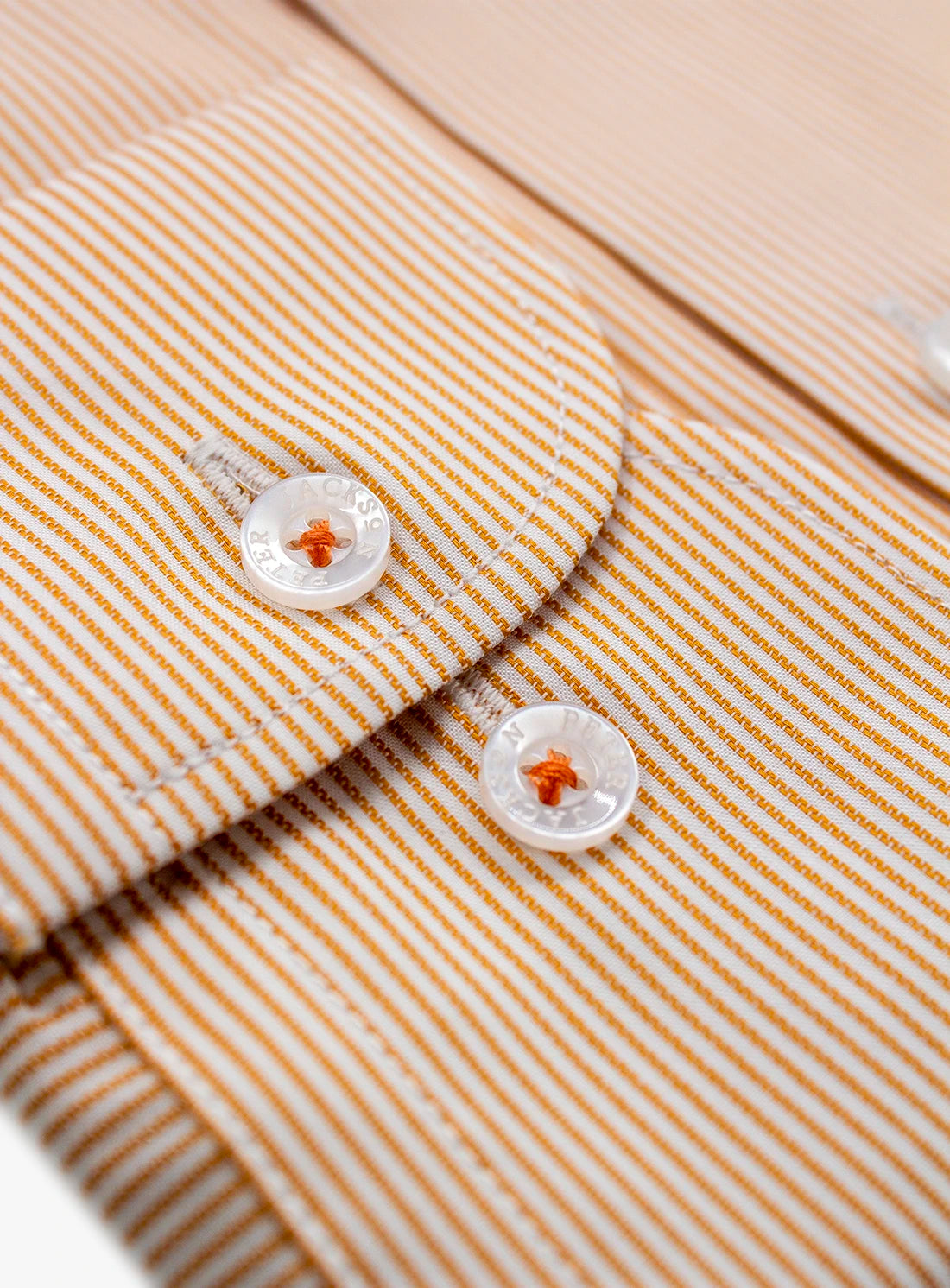Close-up of a striped shirt with buttons on a beige background