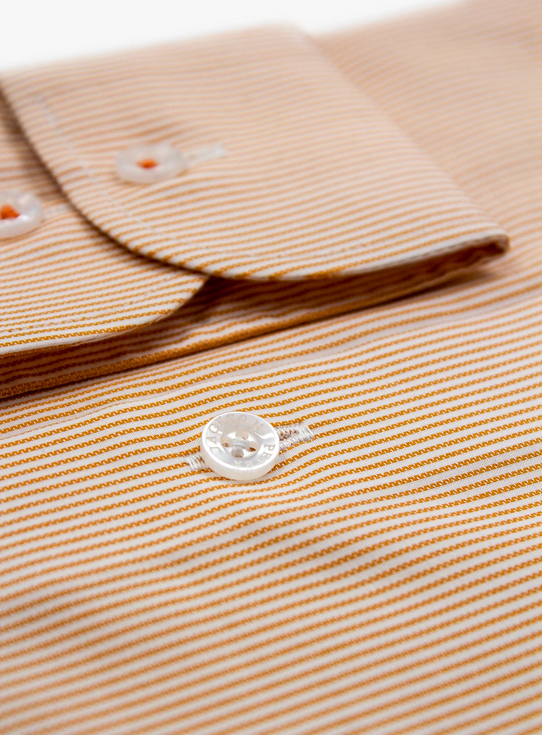 Close-up of a beige striped shirt with buttons on a white background