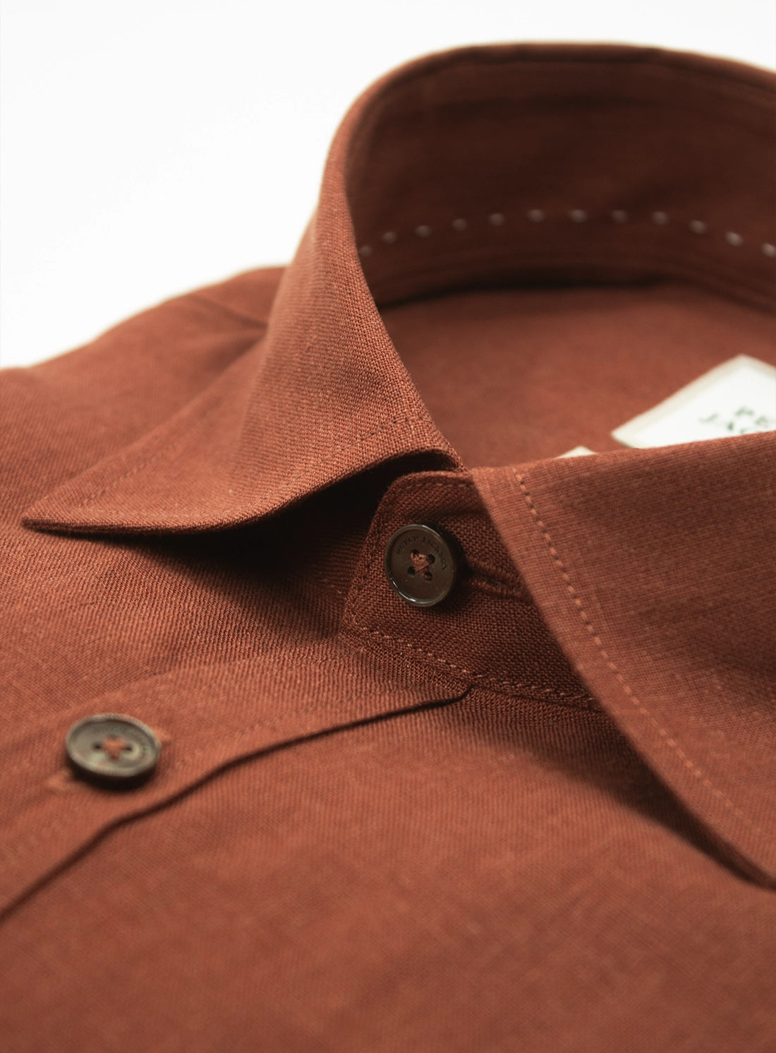 Close-up of a brown shirt collar with buttons on a white background