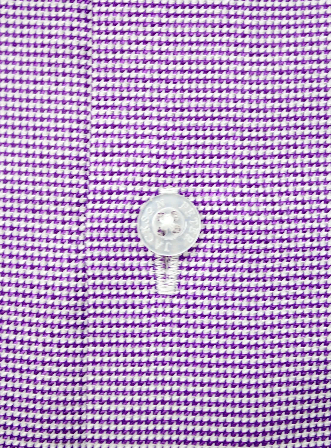 Close-up of a purple houndstooth pattern with a button on a fabric background