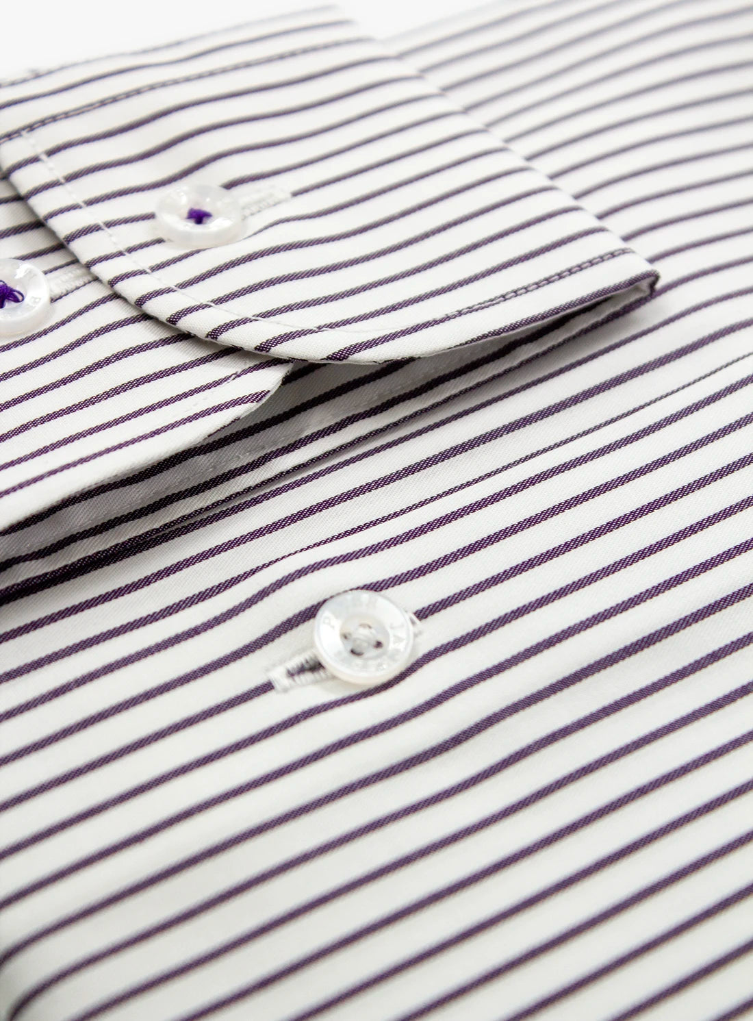 Close-up of a striped shirt with a button, showing details of the fabric and pattern.