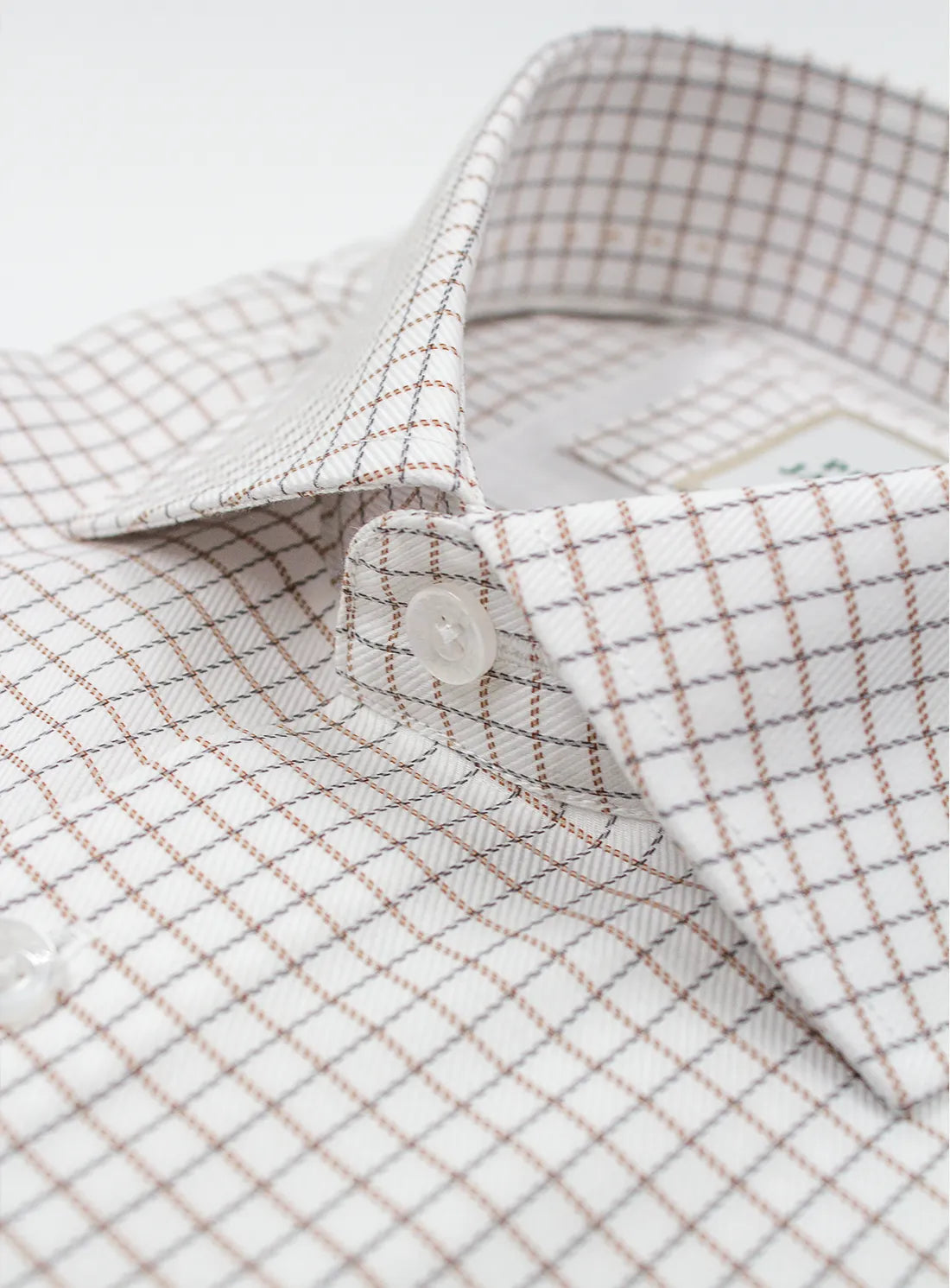 Close-up of a checkered shirt with a button on a light background