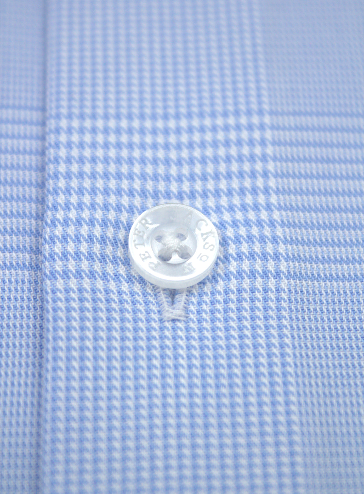 Close-up of a branded button and sky blue and white plaid cotton on the Milan shirt