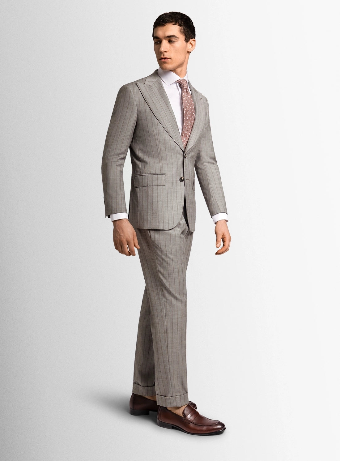 Man wearing a gray checkered suit with a white shirt and brown shoes on a light gray background