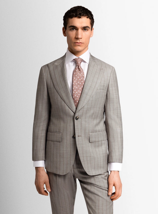 Man wearing a gray suit with a white shirt and patterned tie on a light gray background