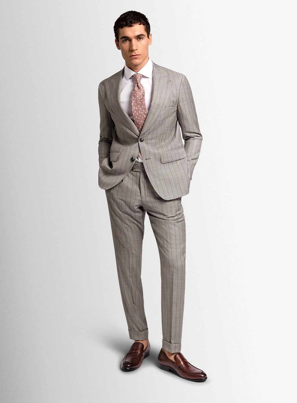 Man wearing a gray checkered suit with a white shirt and patterned tie on a light gray background